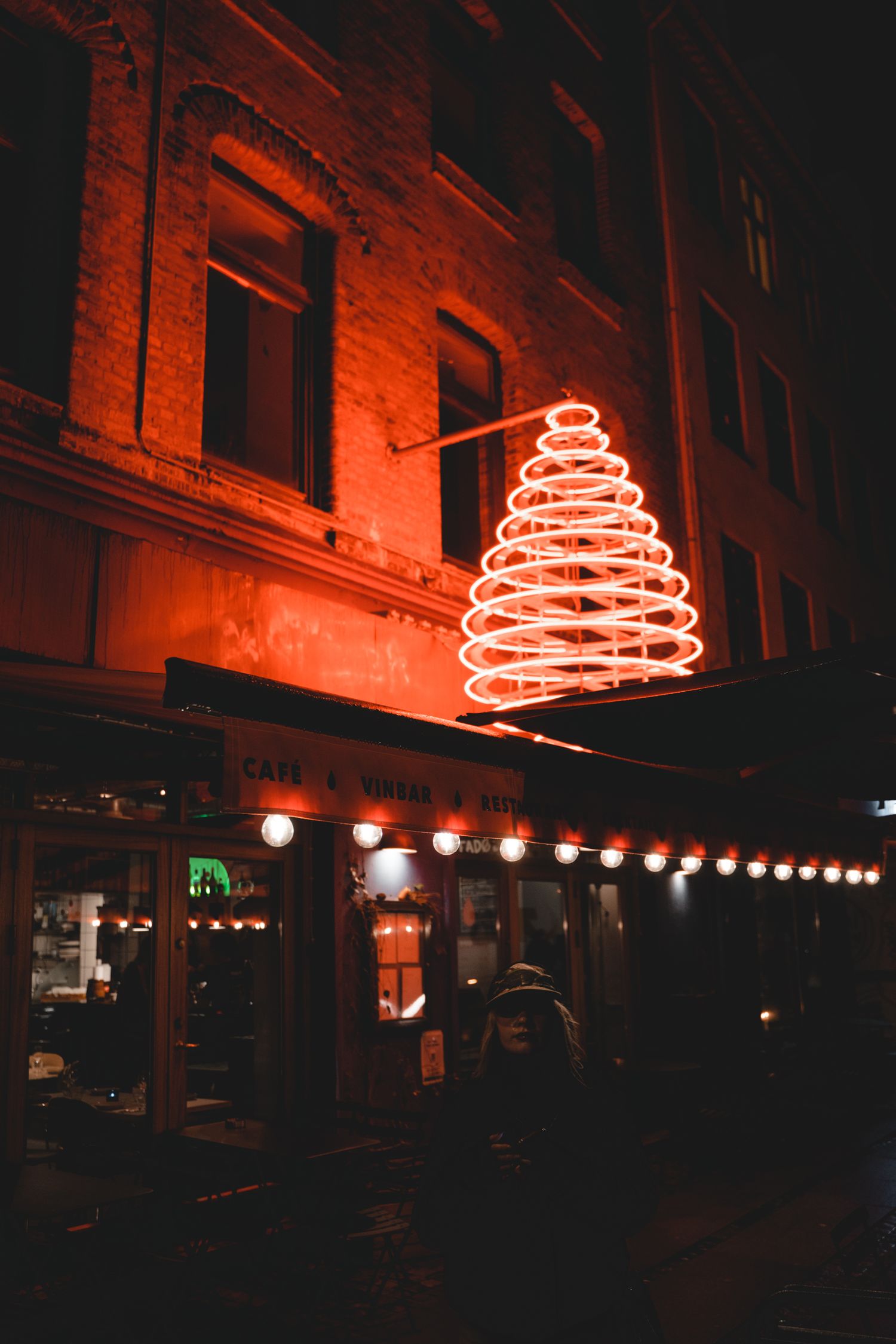 Spiral-shaped neon orange lights illuminate dark urban street at night.