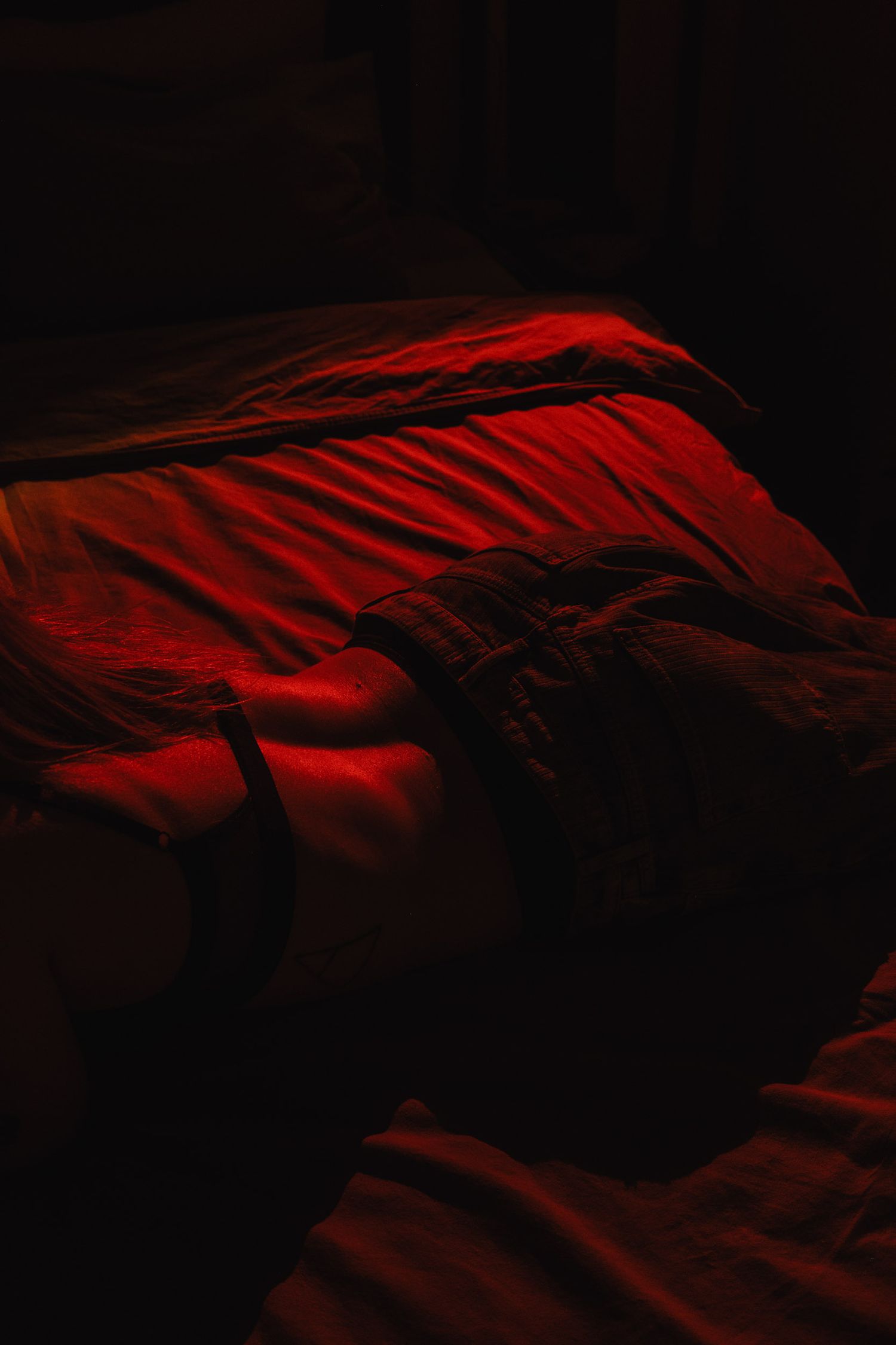 Red fabric or bedding photographed in dark dramatic lighting creating abstract shapes.