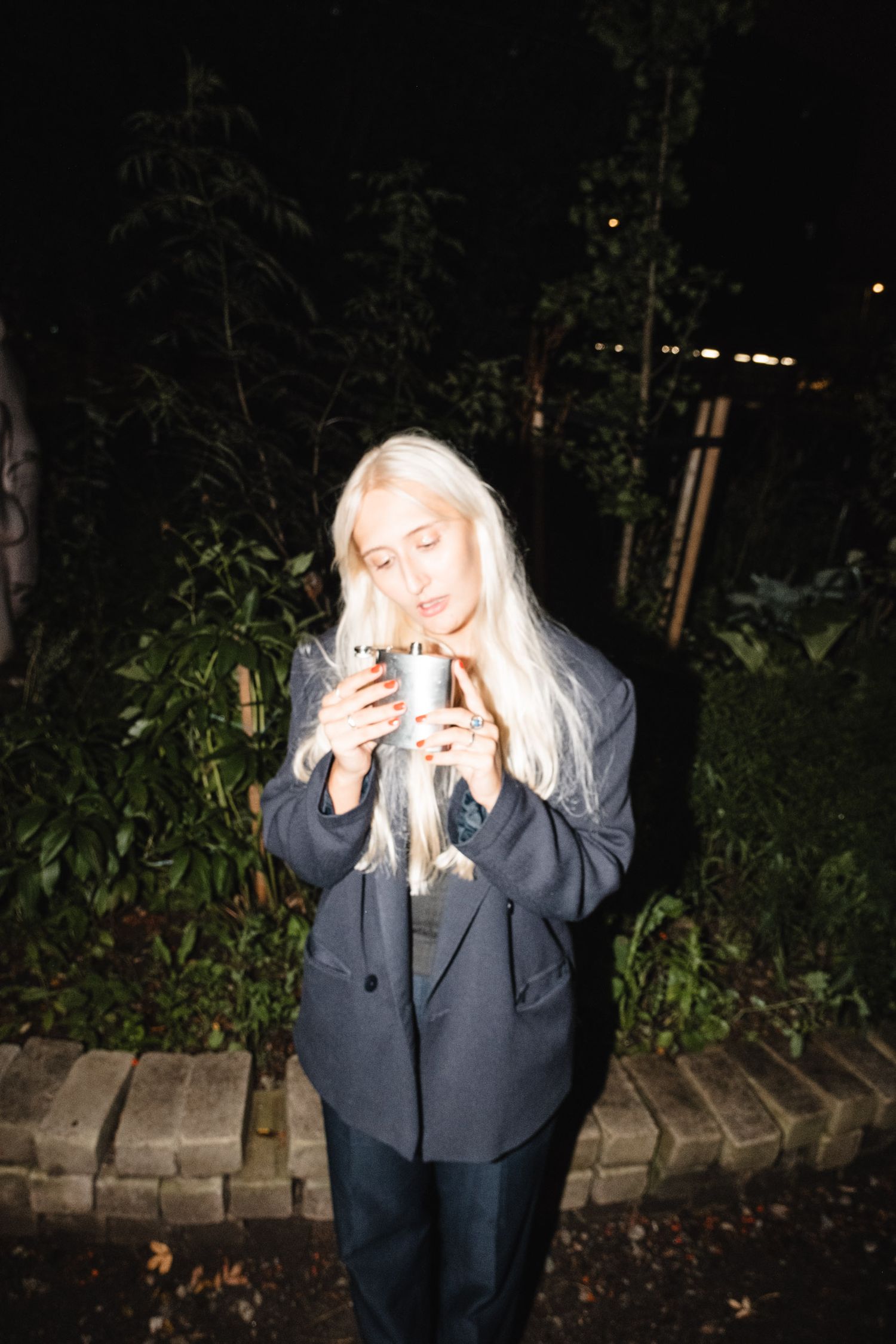 Person in a grey hoodie posing dramatically outdoors at night.
