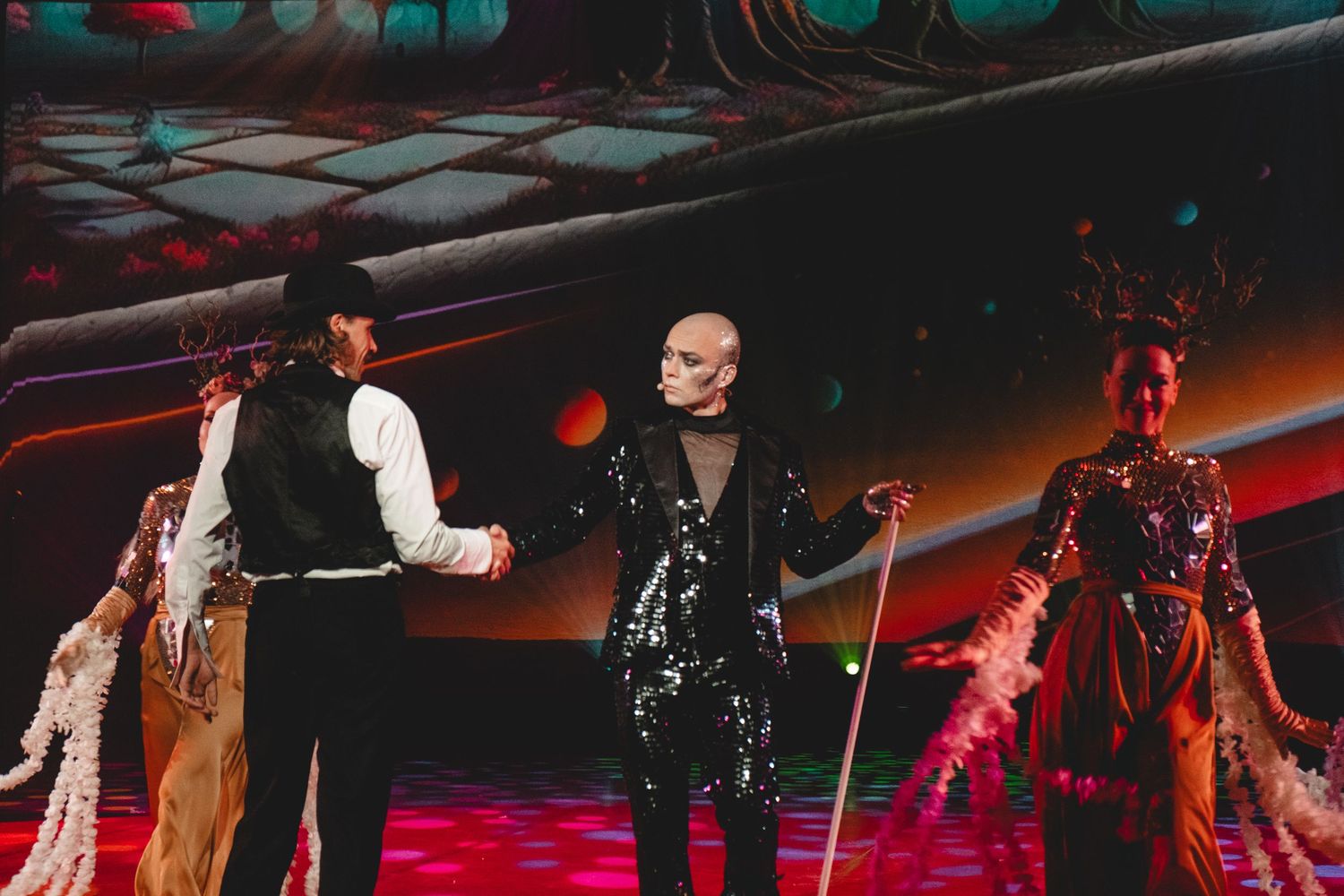 Performers on stage with dramatic red lighting and theatrical effects.