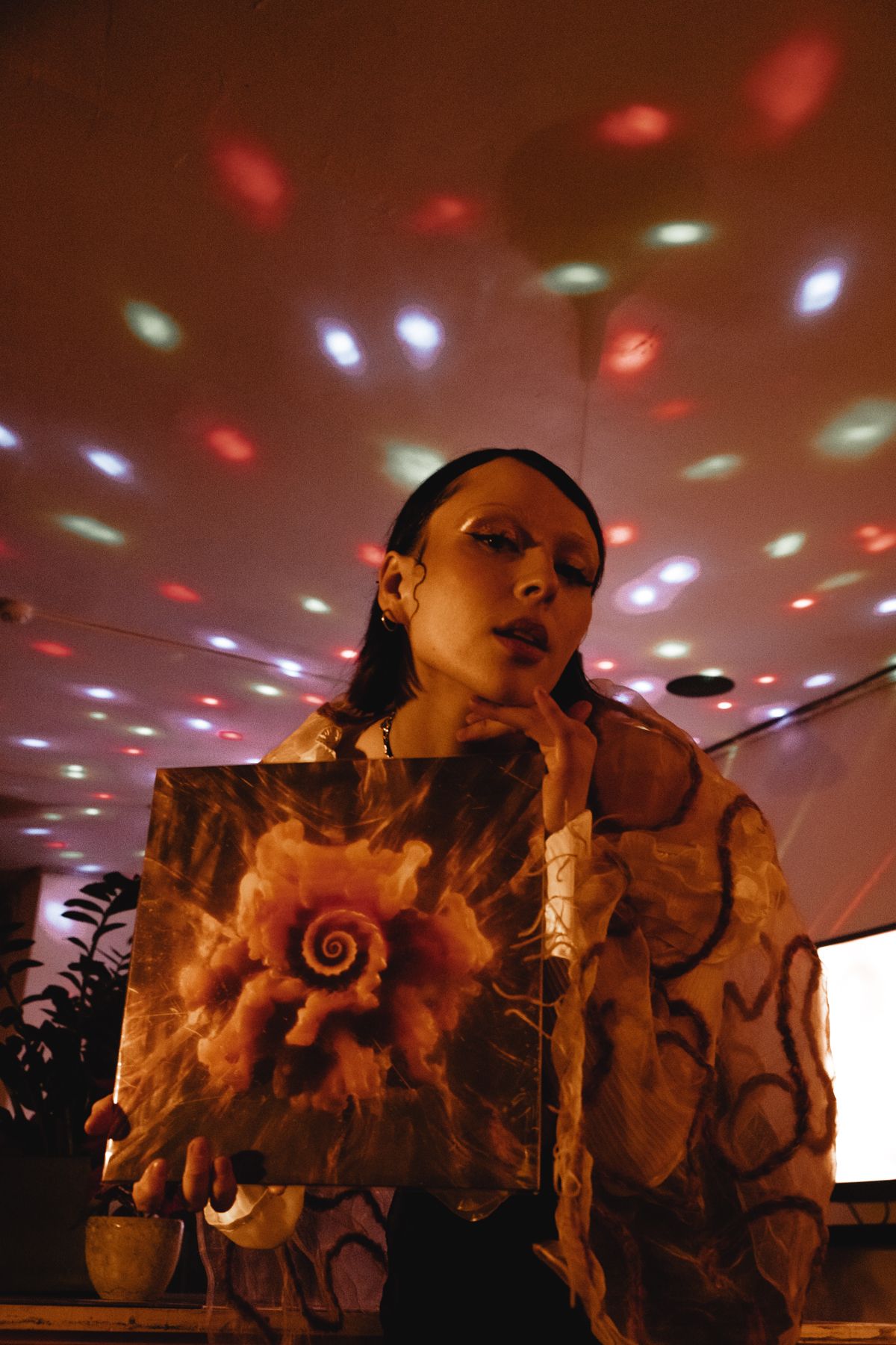 Concert performer under disco lights wearing patterned outfit during live show.