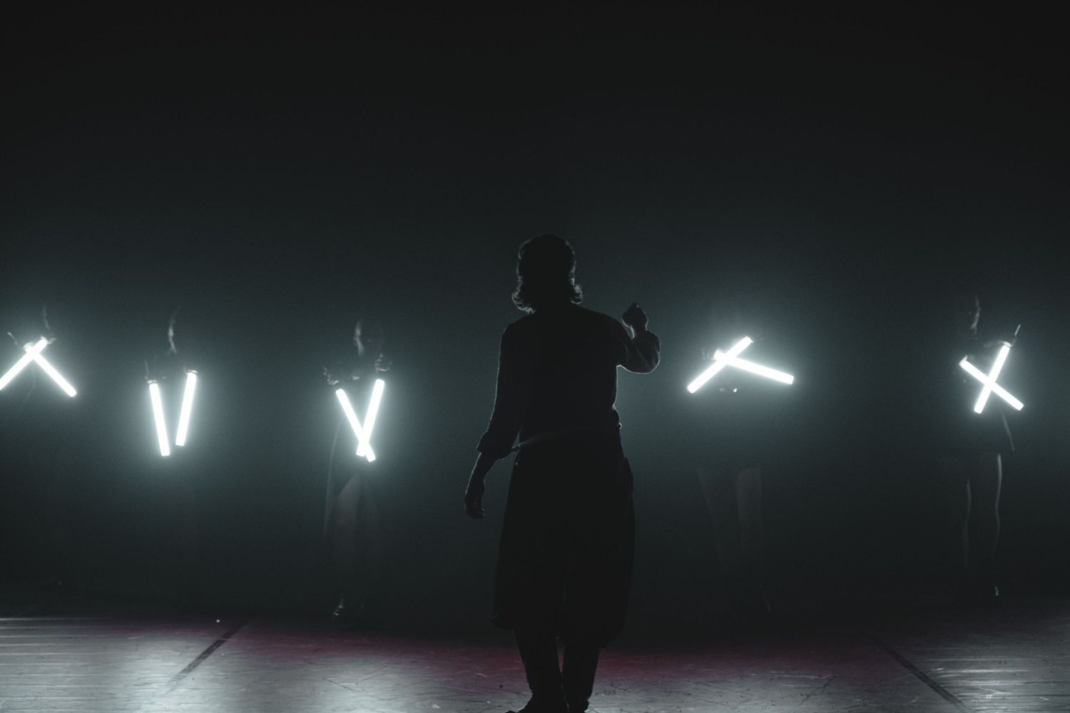 Backlit performers creating dramatic silhouettes against bright white stage lights.
