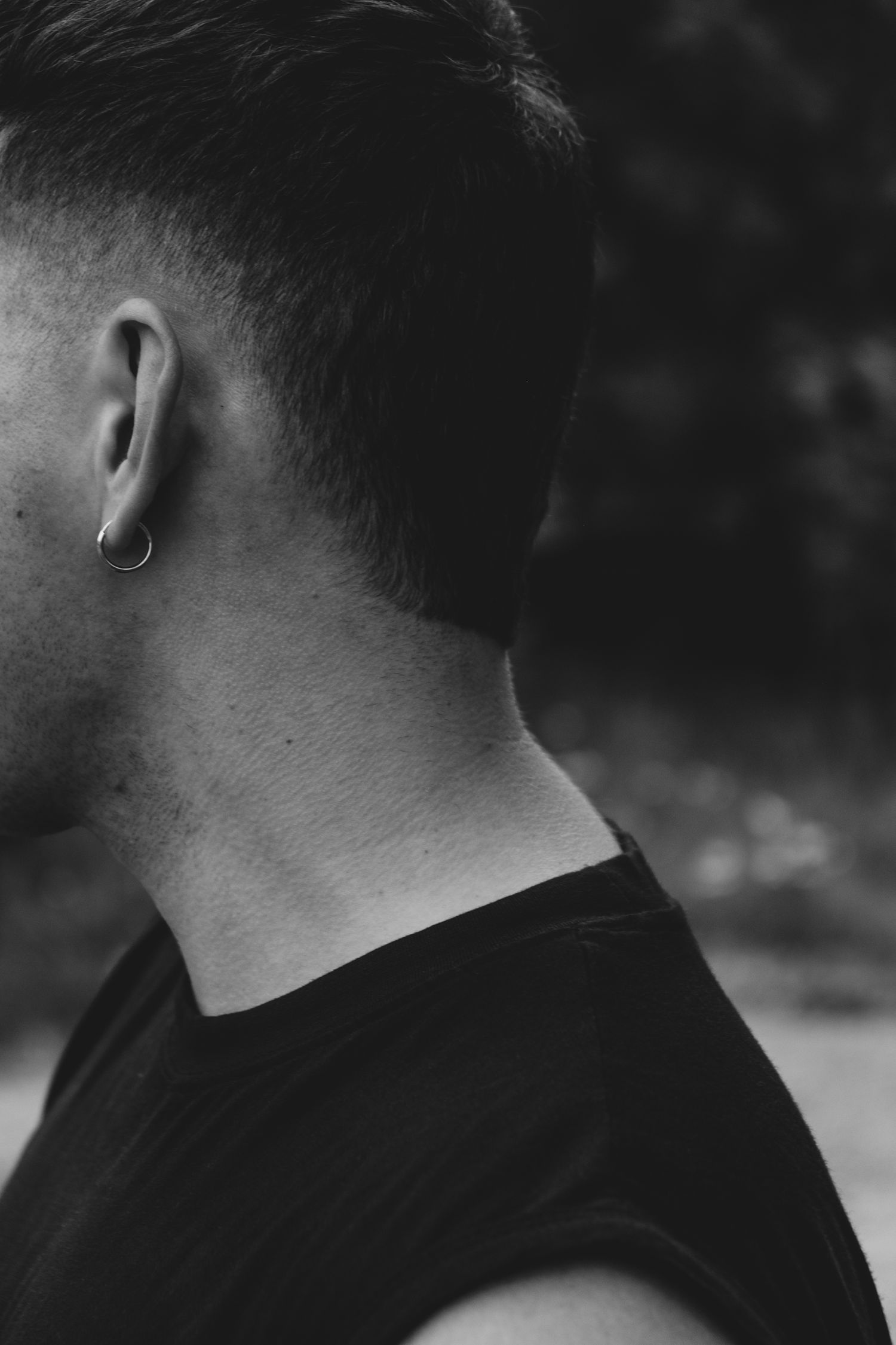 Close-up black and white profile shot showing ear piercing and short haircut.