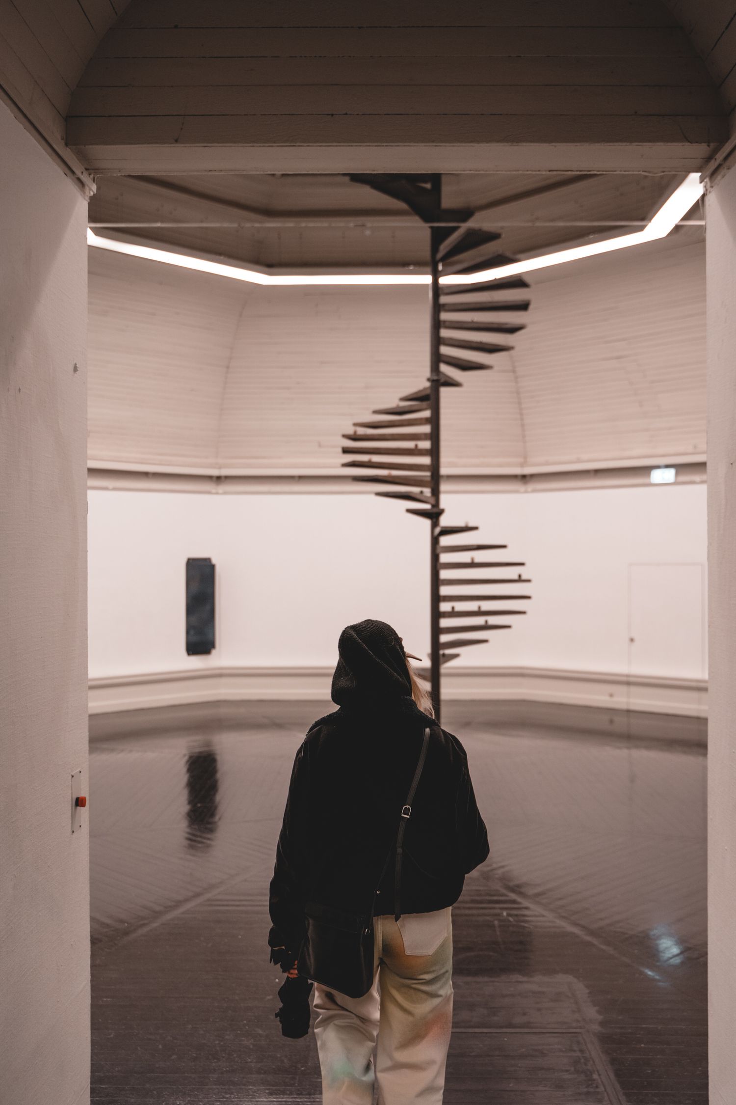 Modern minimalist white corridor with curved walls and lighting fixtures.