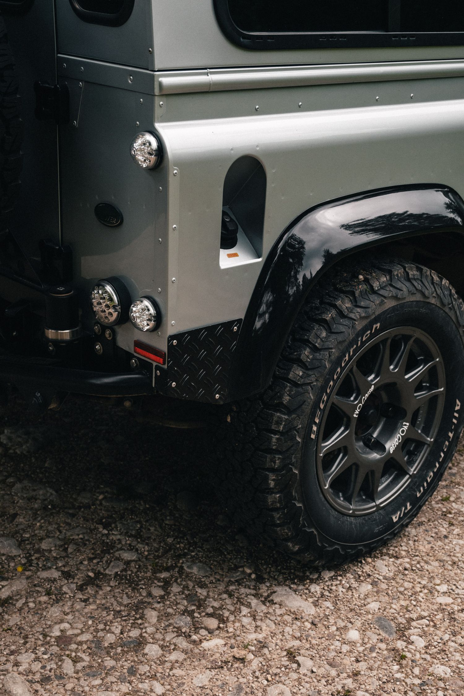 Close-up view of rugged off-road tires and silver wheels on a vehicle.