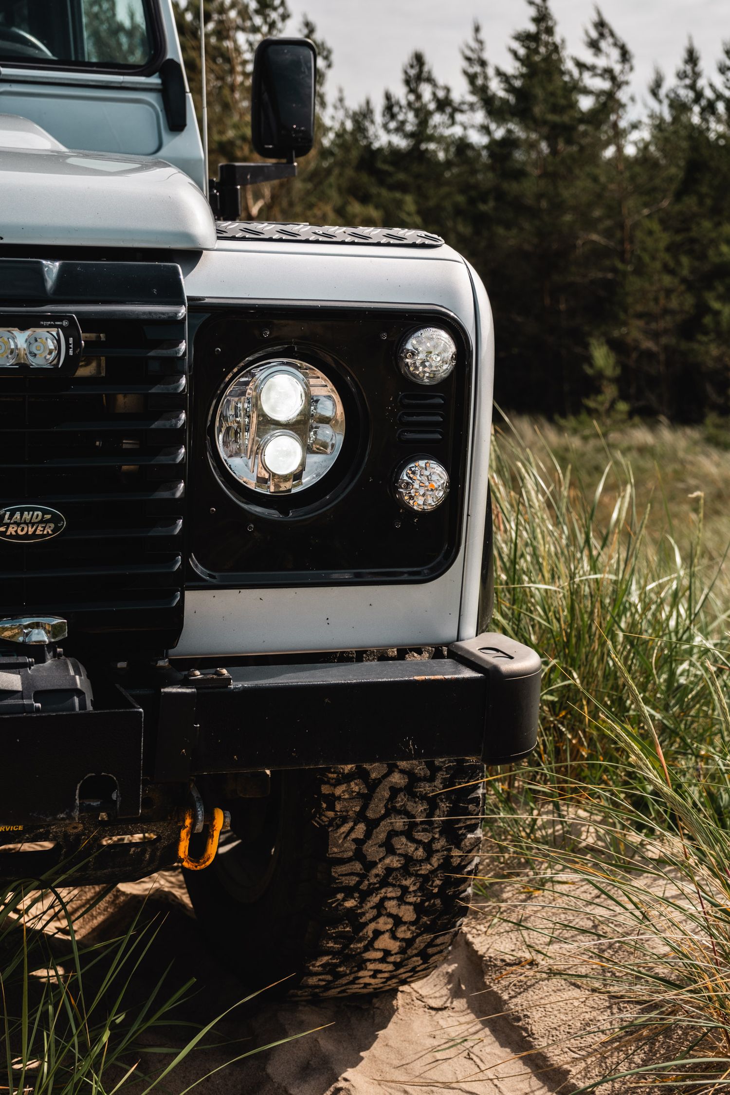 Close-up of modern Land Rover Defender headlights and grille details.