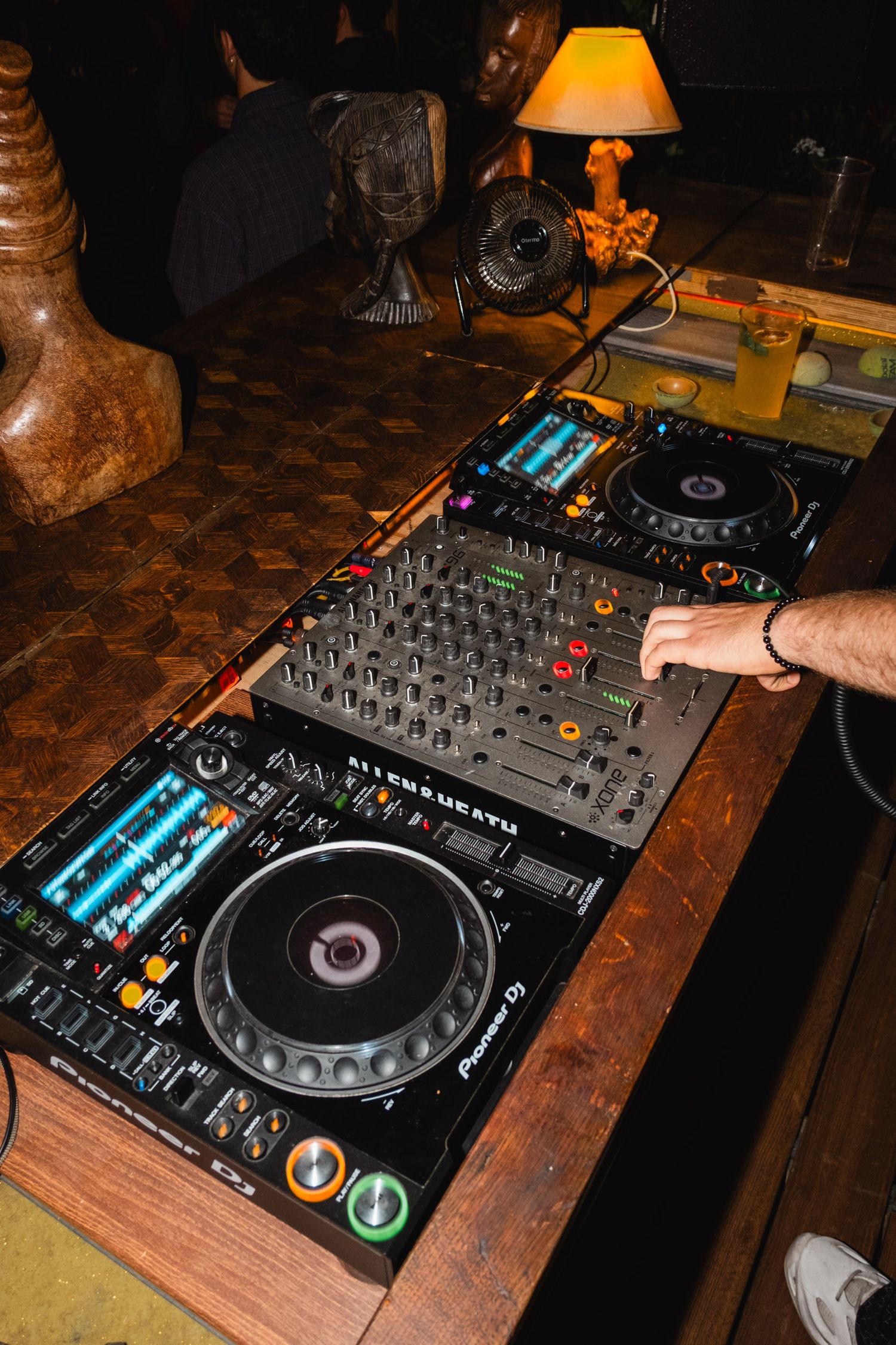 Professional DJ equipment setup with turntables and mixer on wooden surface.