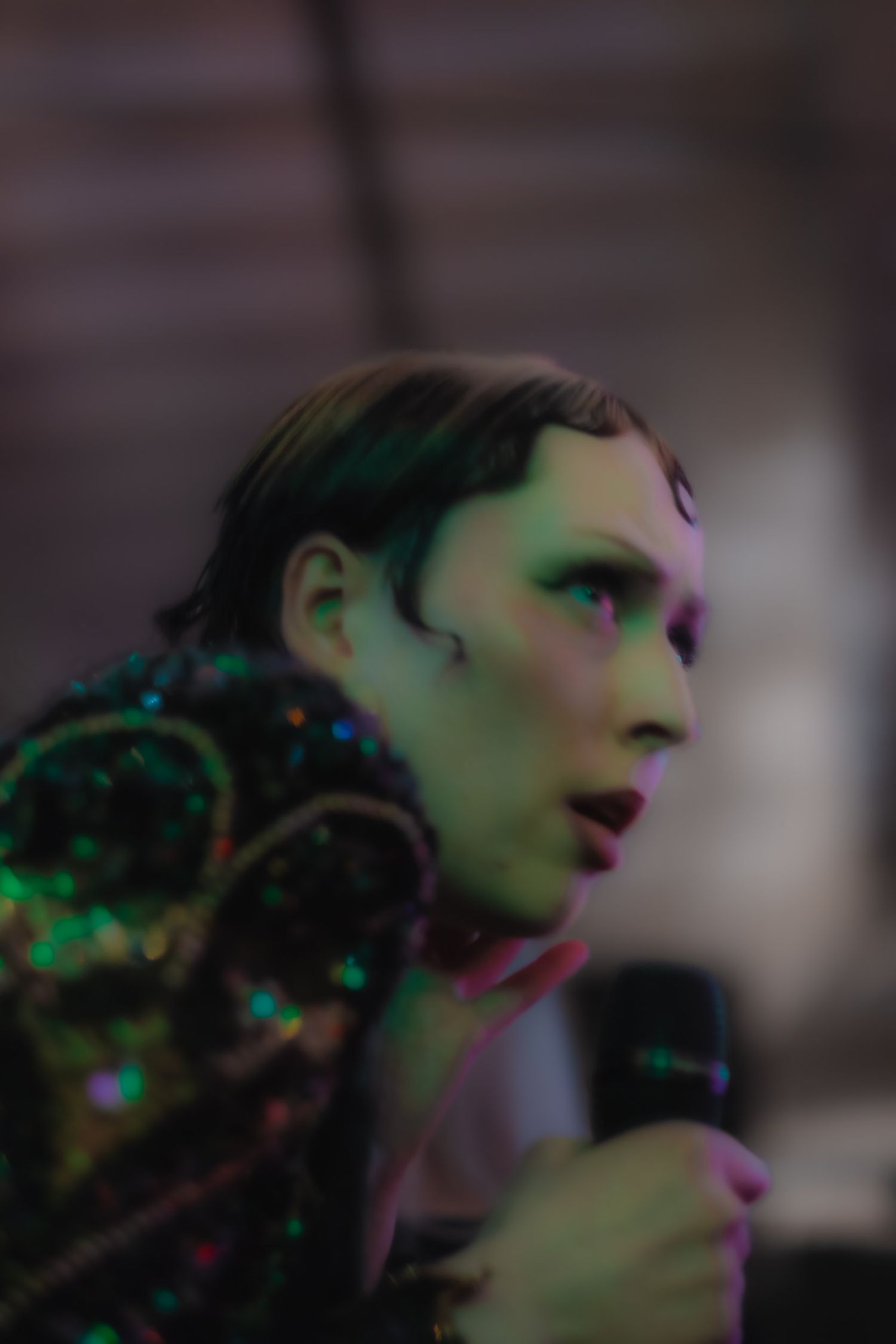 Performance scene bathed in dramatic green and pink lighting effects.