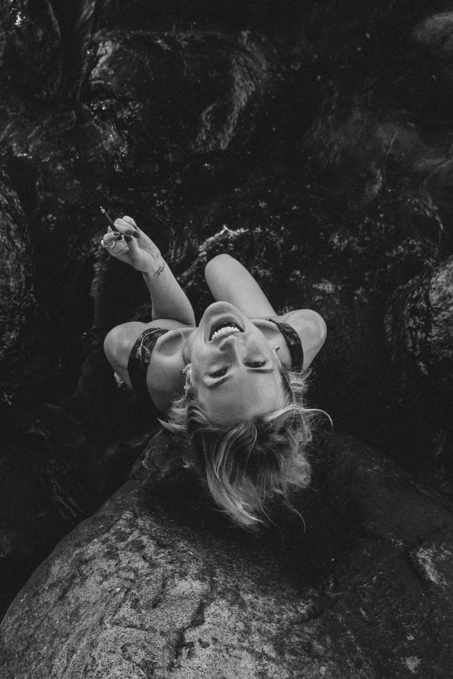 Artistic black and white portrait showing dramatic poses against a dark rocky background.