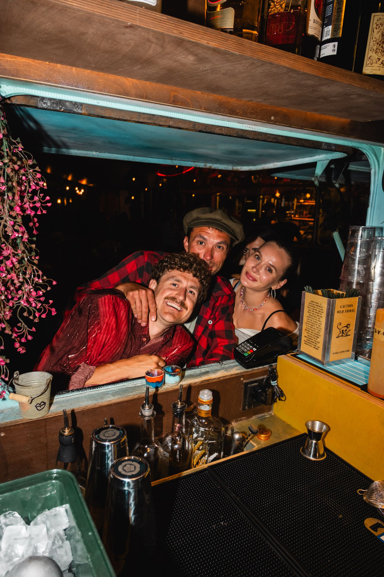 Friends having fun behind a bar counter at night.