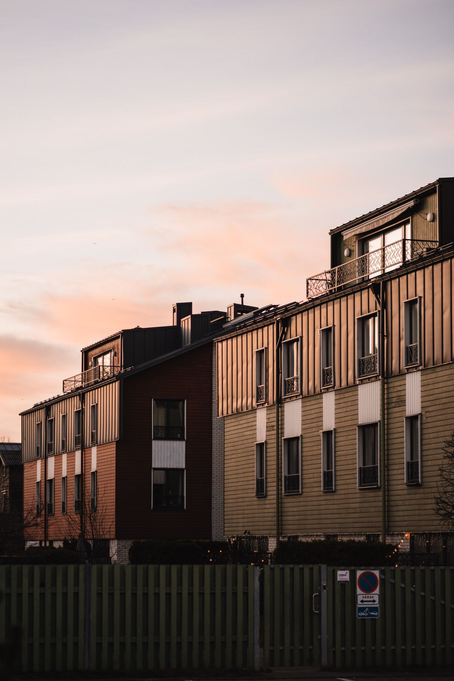 Modern apartment buildings silhouetted against a pastel sunset sky.