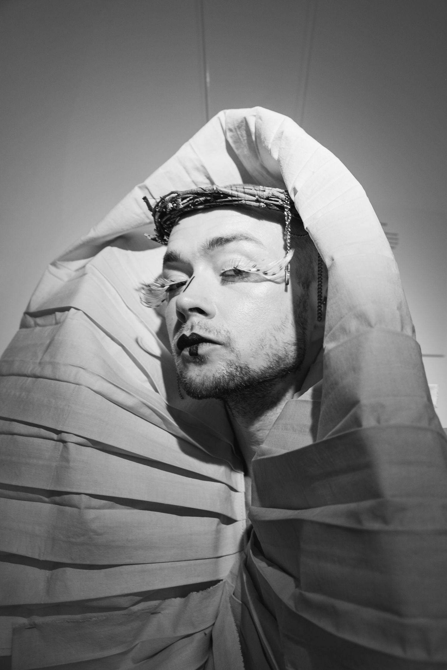 Dramatic black and white portrait with fabric wrapped around subject in artistic pose.