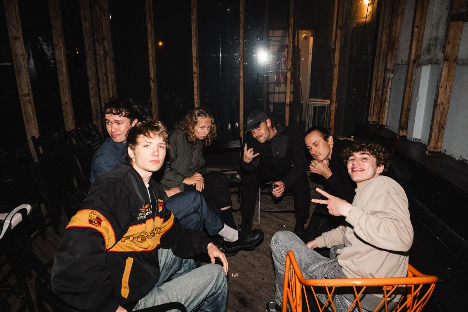 People socializing outdoors on orange chairs at night.