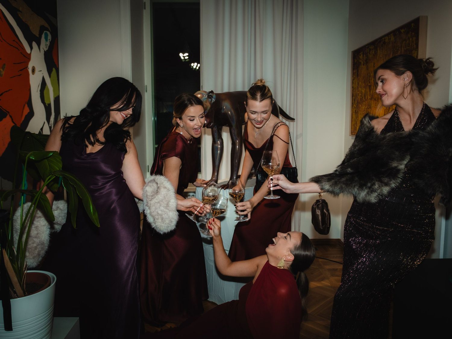 People dancing and socializing at a party in a dimly lit room with curtains in the background.