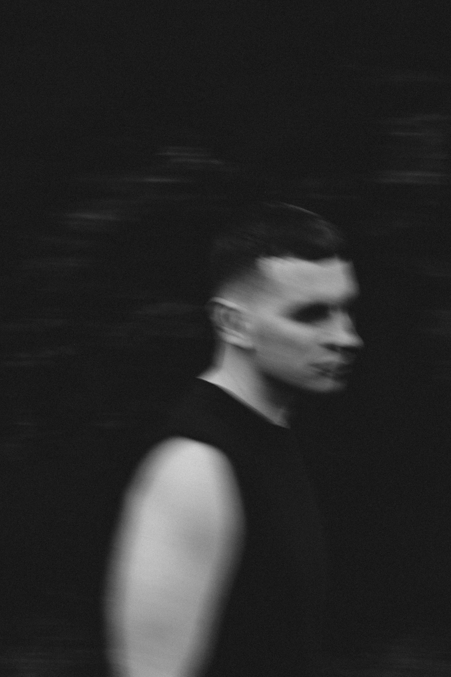 Artistic motion blur portrait in black and white with dramatic side lighting.