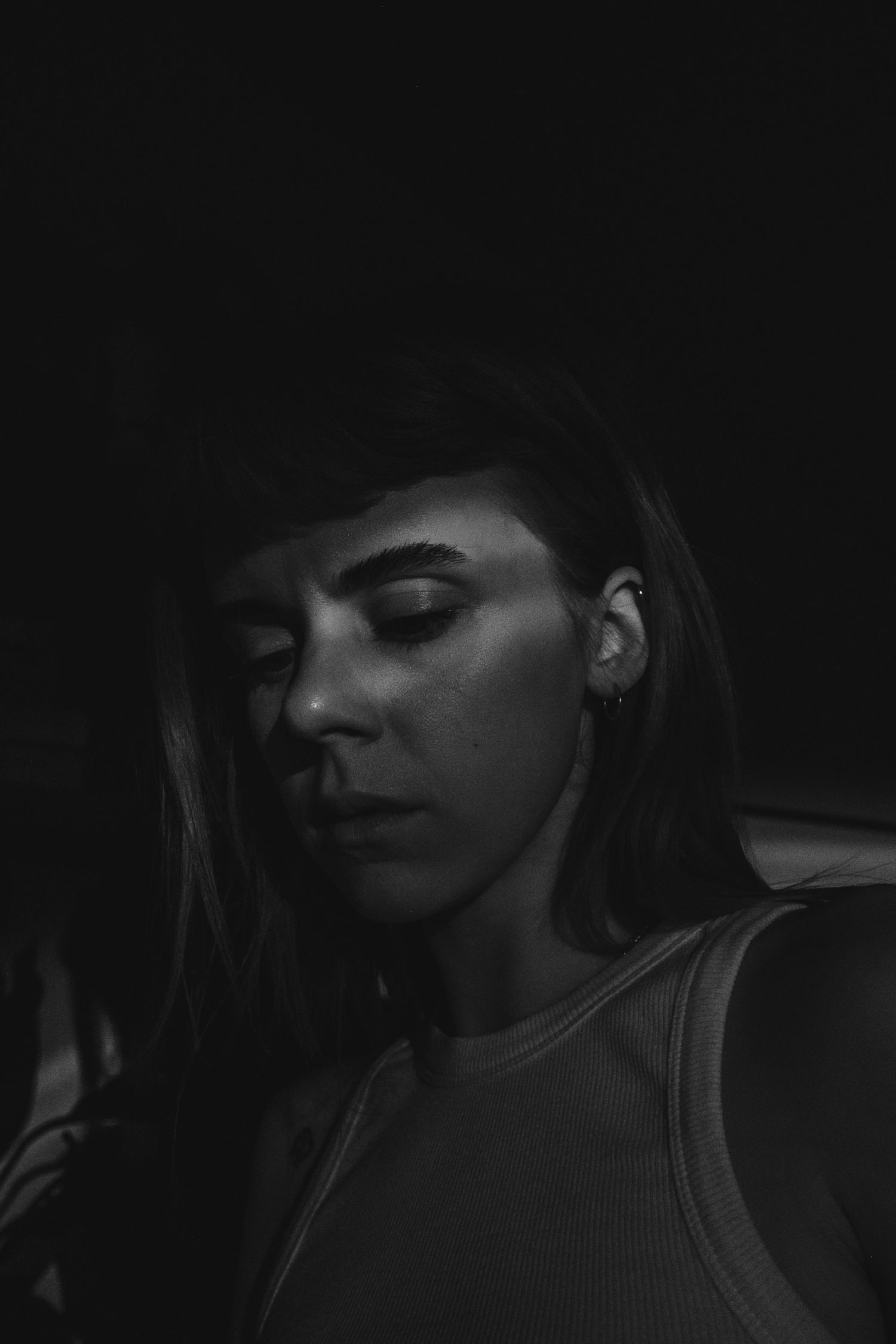 Moody black and white portrait shot in low-key lighting.