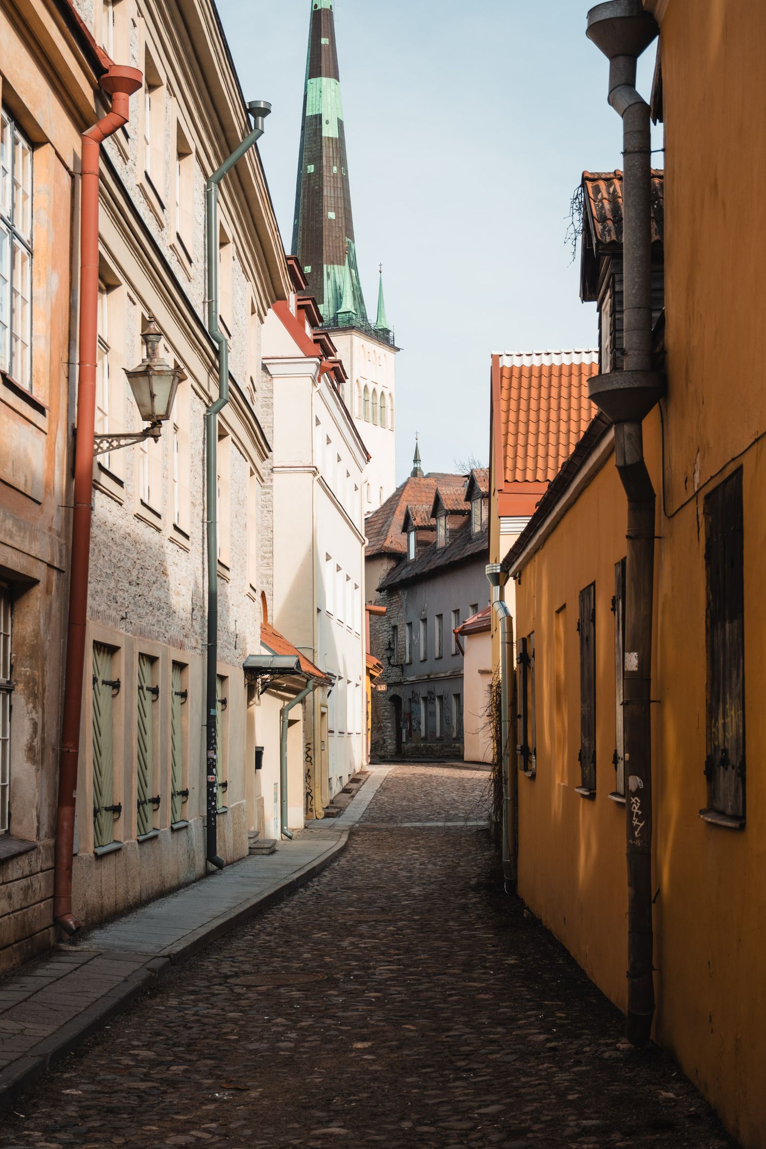 Picturesque medieval street with historic buildings and church spire visible in the distance.