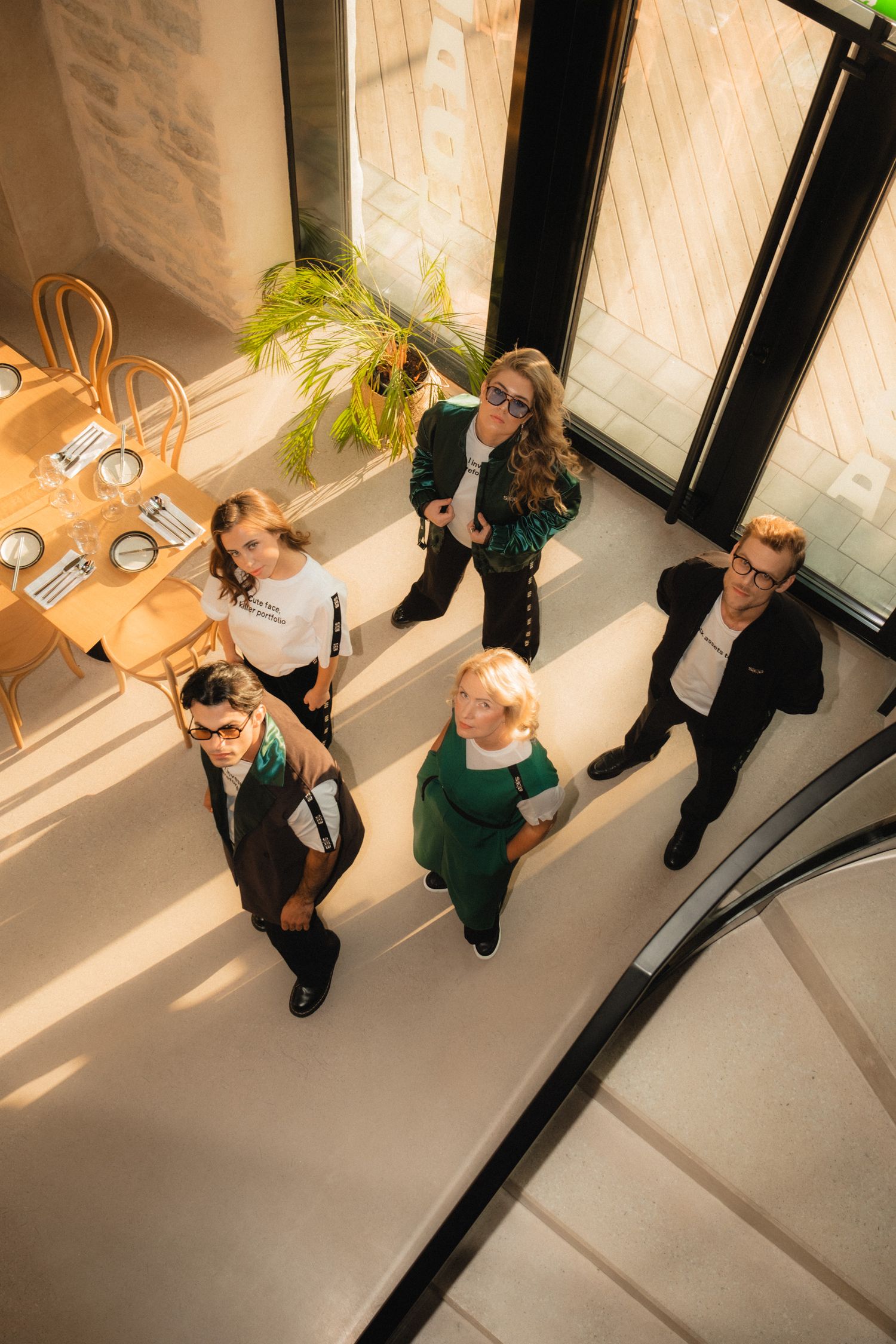 High angle view of a group of people standing in a modern office space with natural lighting and curved staircase.