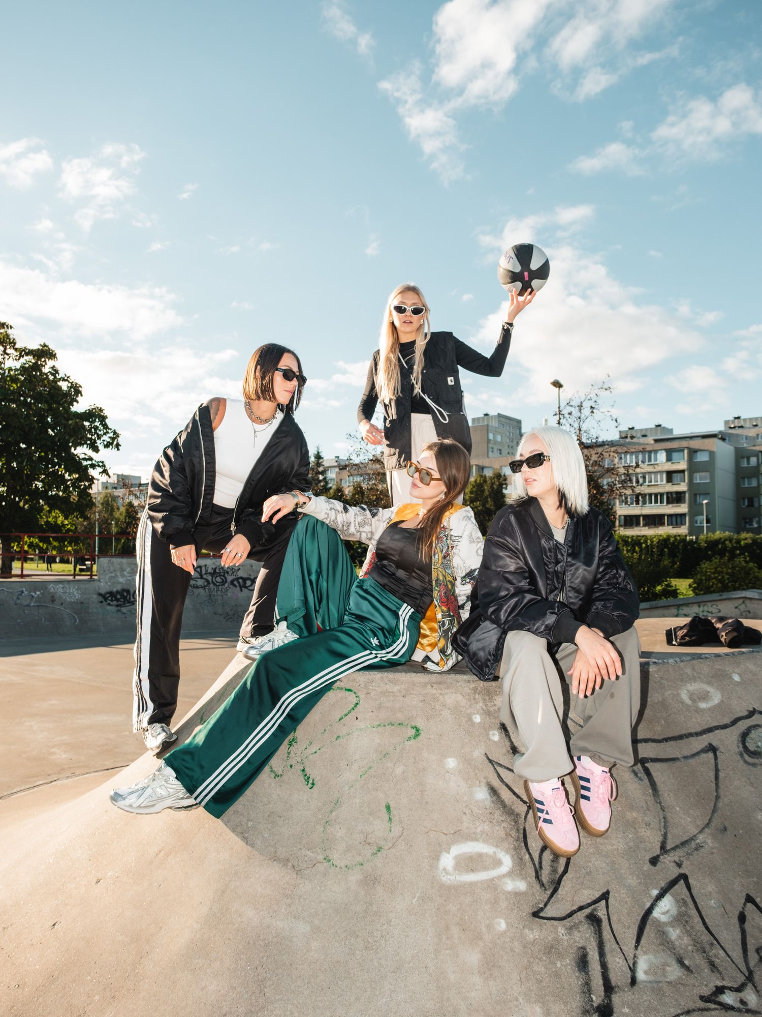 Group in sporty outfits posing with basketball on concrete ramp outdoors.