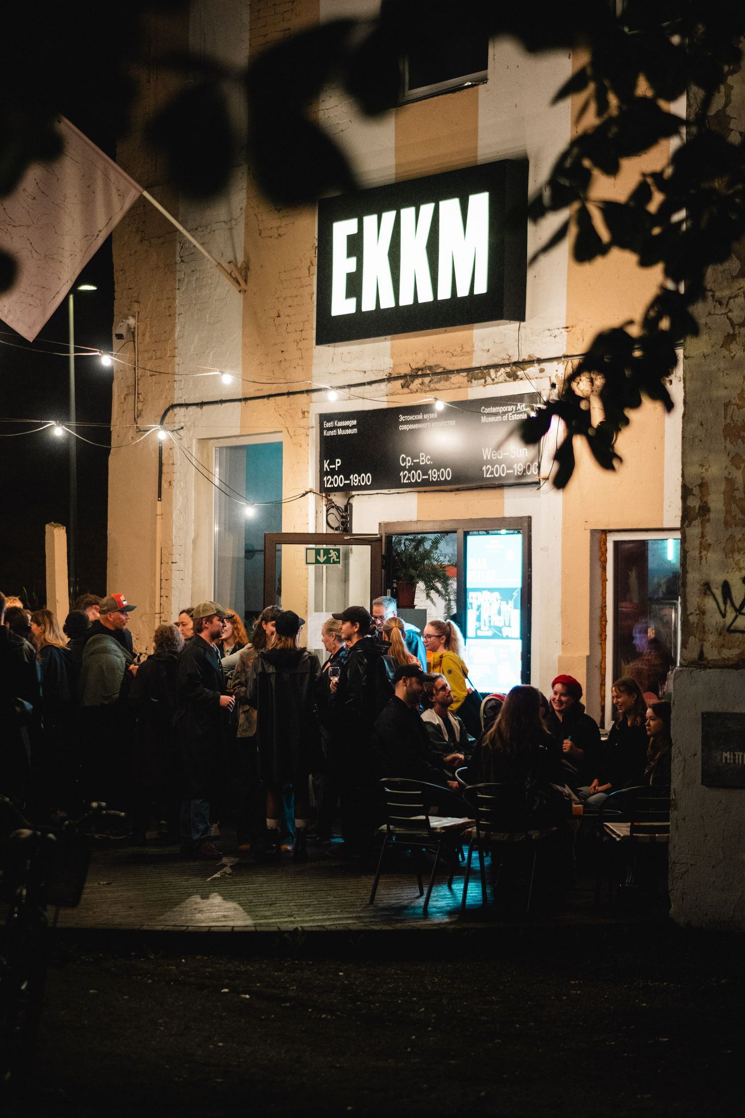 Nighttime crowd gathered outside a venue with illuminated EKKM signage.