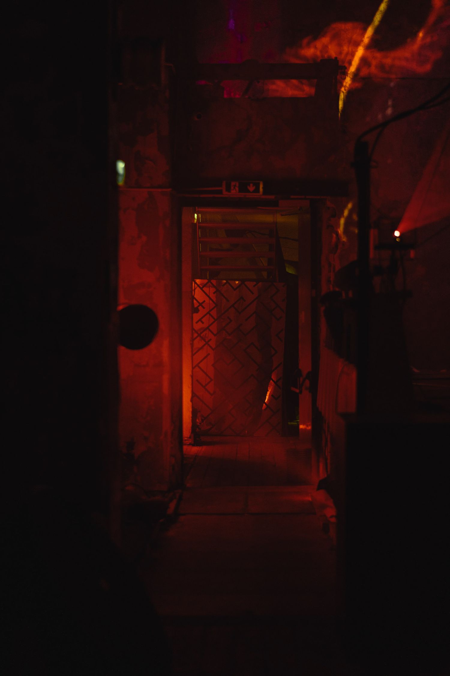 Dark nightclub interior illuminated by red lighting and atmospheric effects.