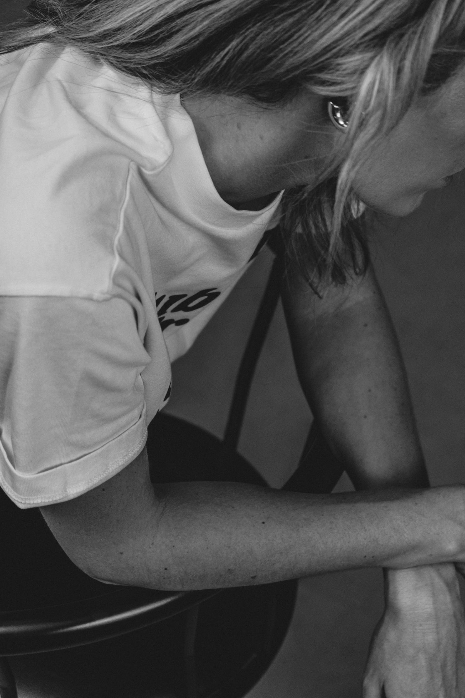 Person in white t-shirt leaning forward in black and white photography.