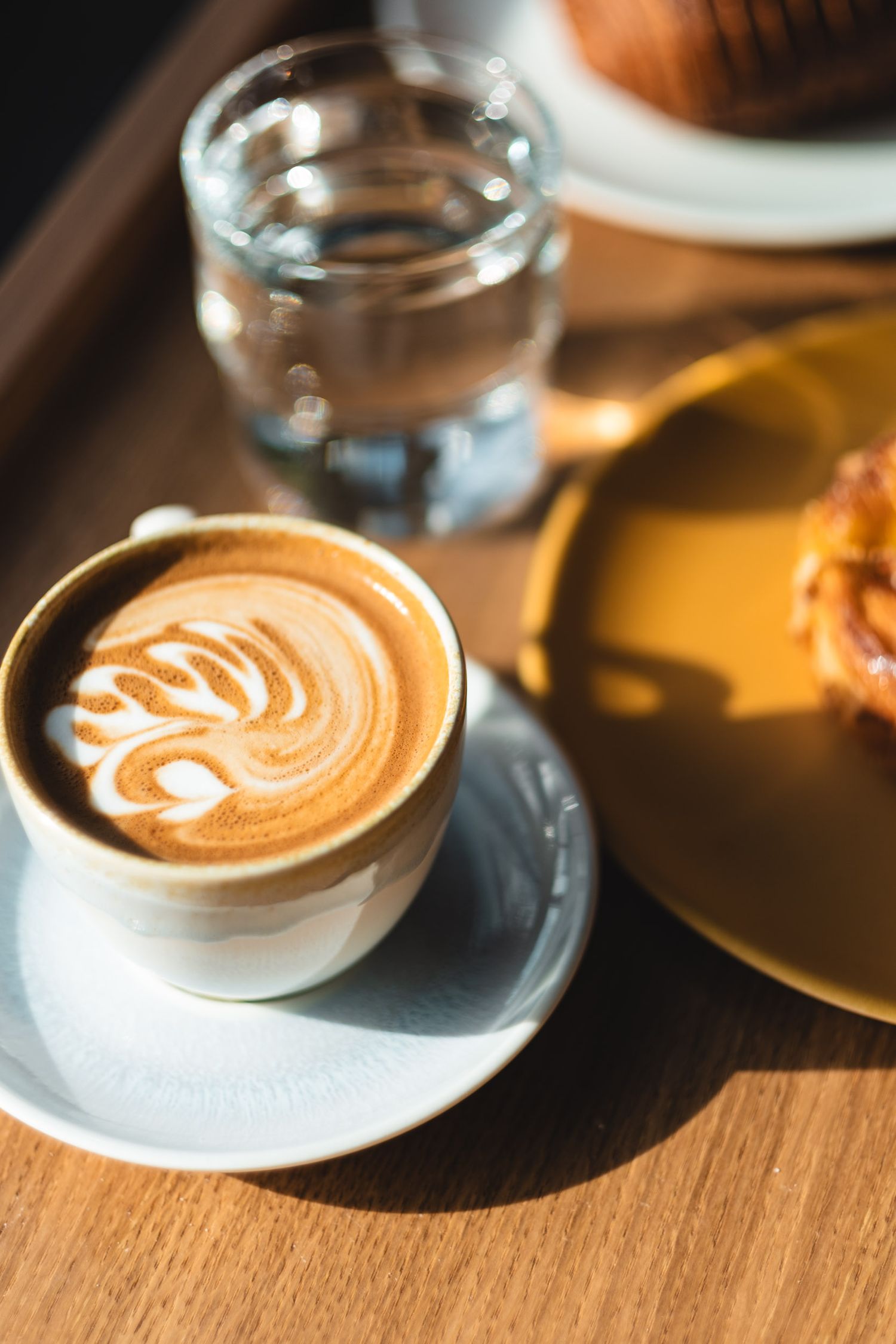 Artfully crafted latte with heart-shaped foam design served alongside a glass of water.