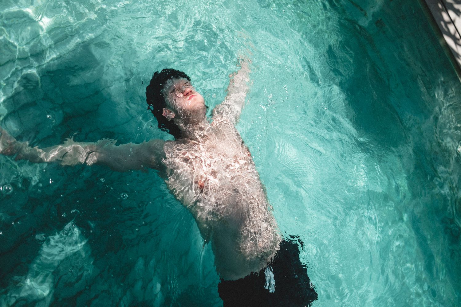 Aerial view of someone swimming in crystal clear turquoise water.