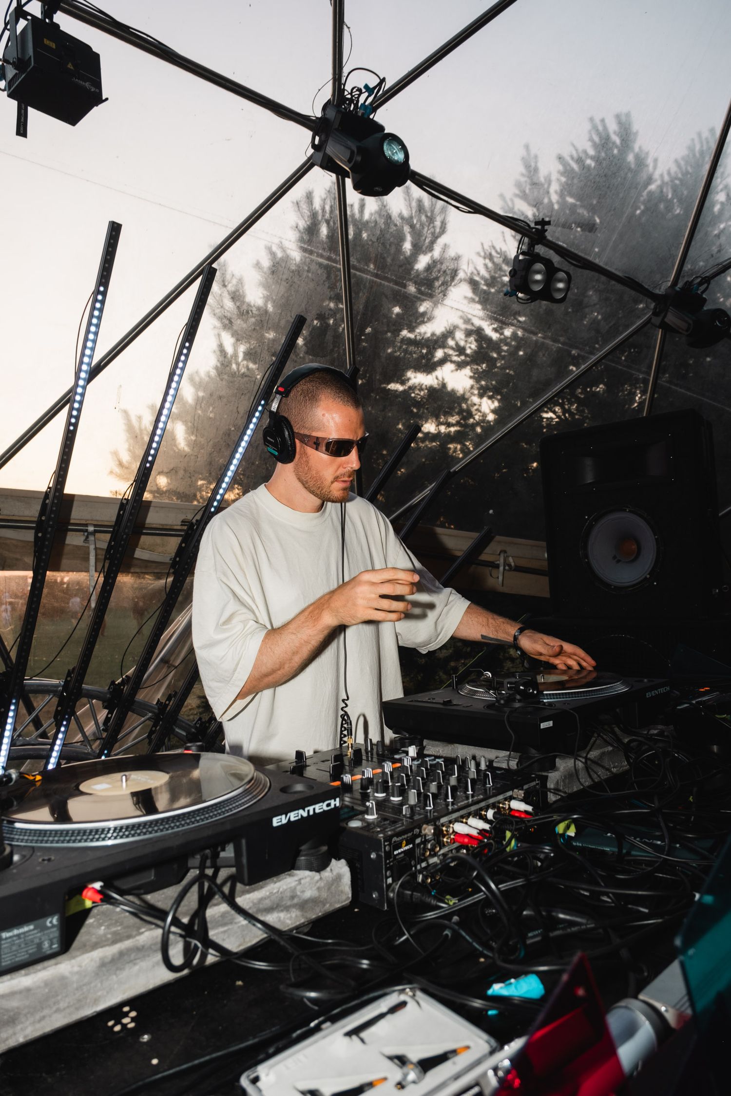 DJ performing at outdoor event with professional equipment and turntables.