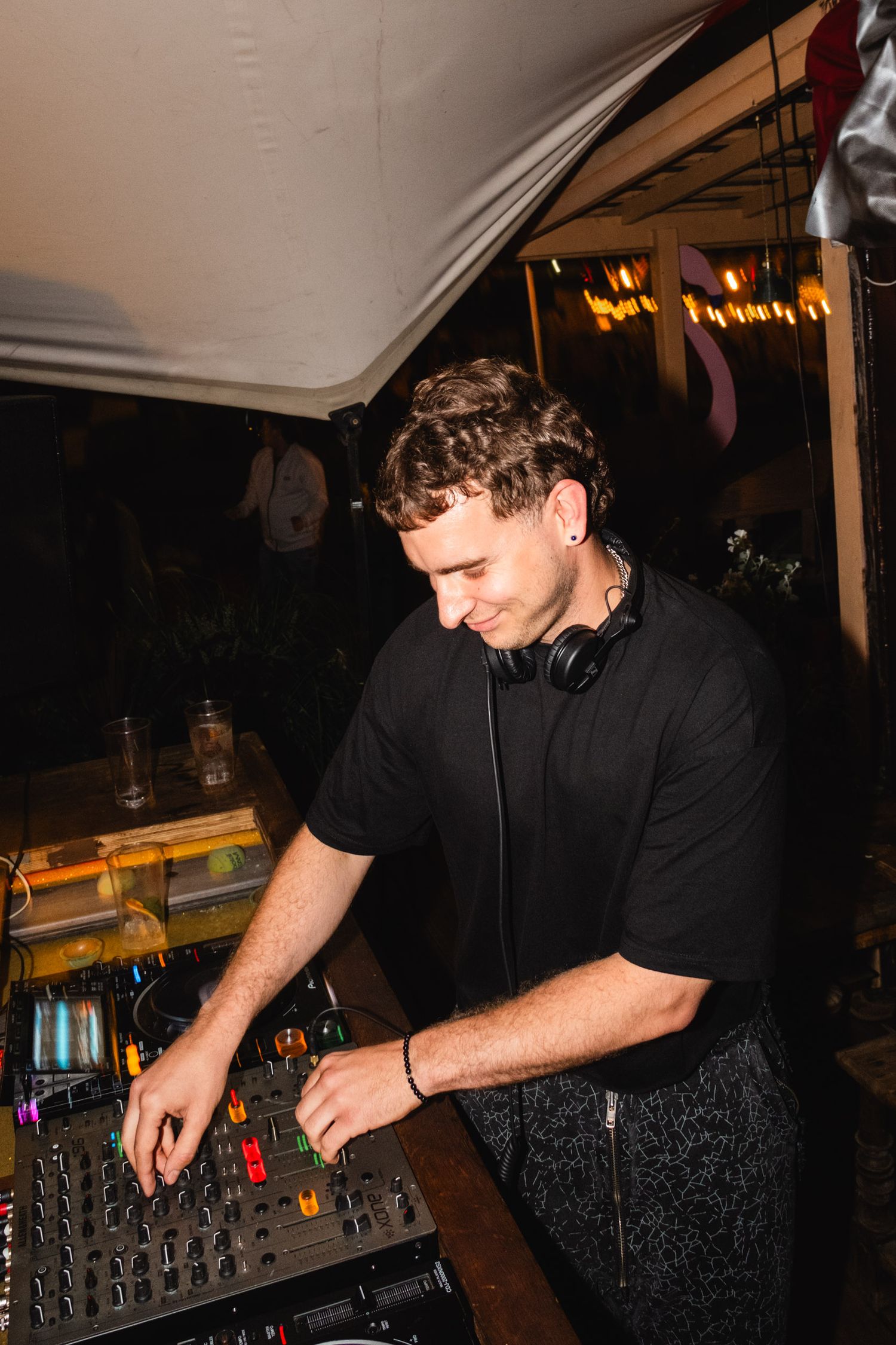 DJ working at a mixing console in dark lighting at an event.