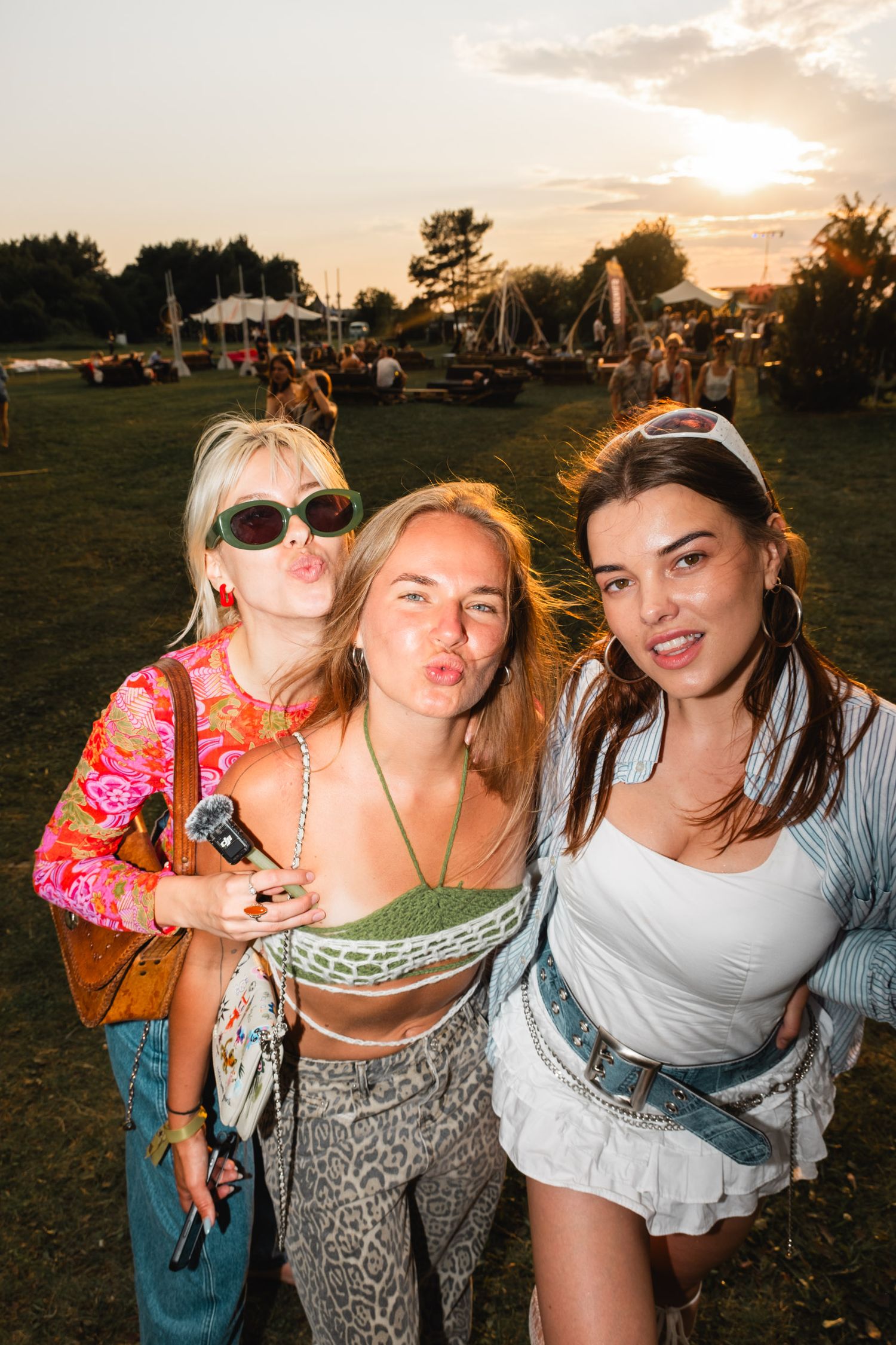 Group enjoying sunset at outdoor festival with playful poses.