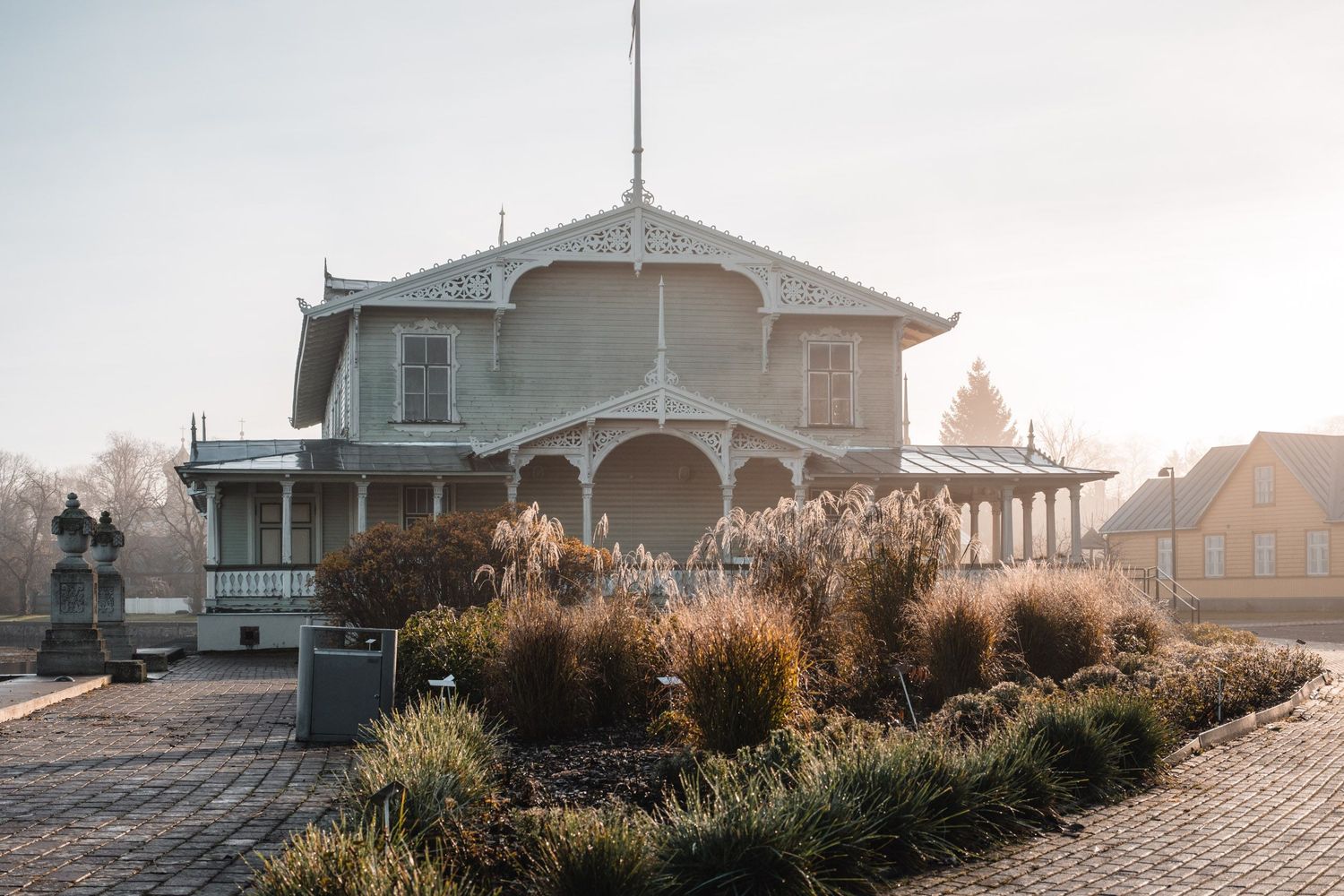 Victorian-style waterfront house with ornate trim and wraparound porch in morning light.