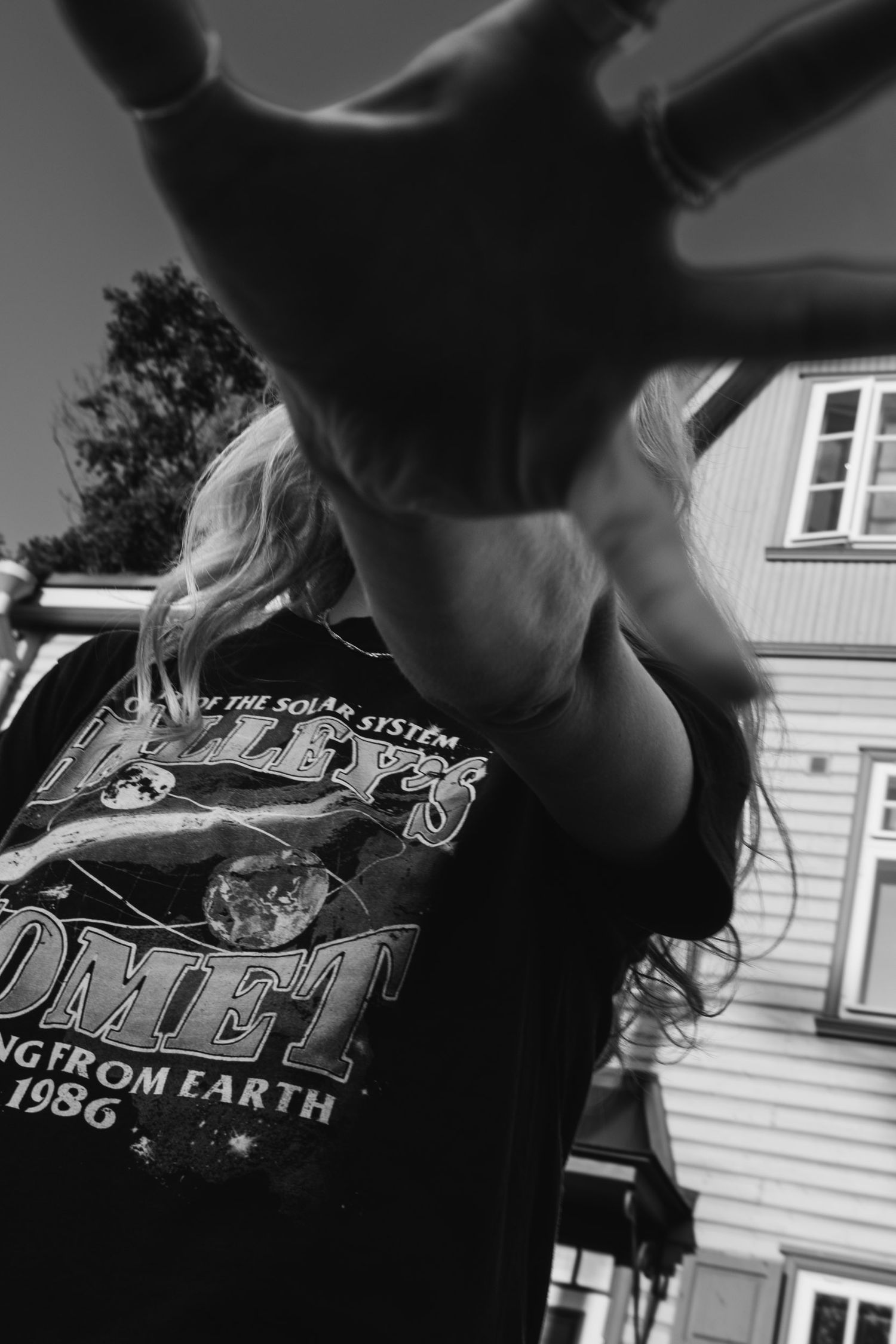 A black graphic t-shirt with text photographed against a wooden building.