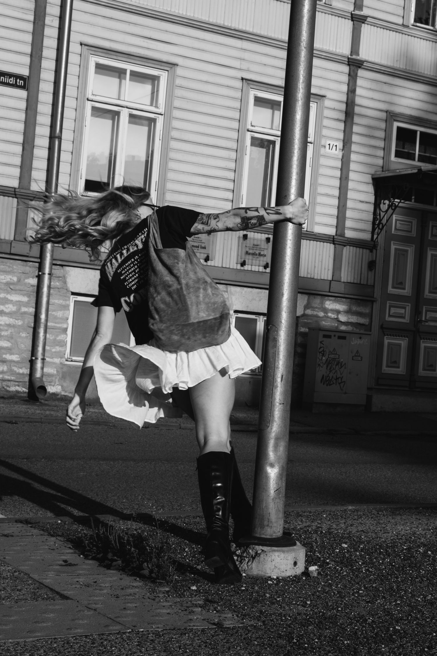 A dynamic street fashion shot featuring a white skirt and boots in black and white.