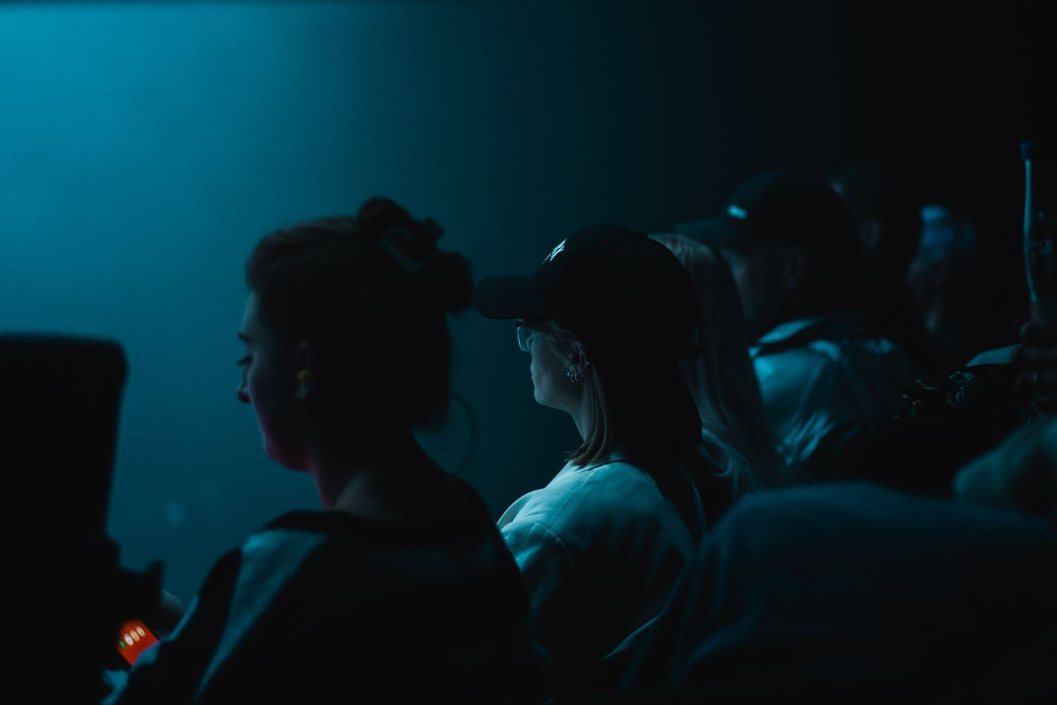 Crowd silhouettes in a dark blue-tinted environment during an event.