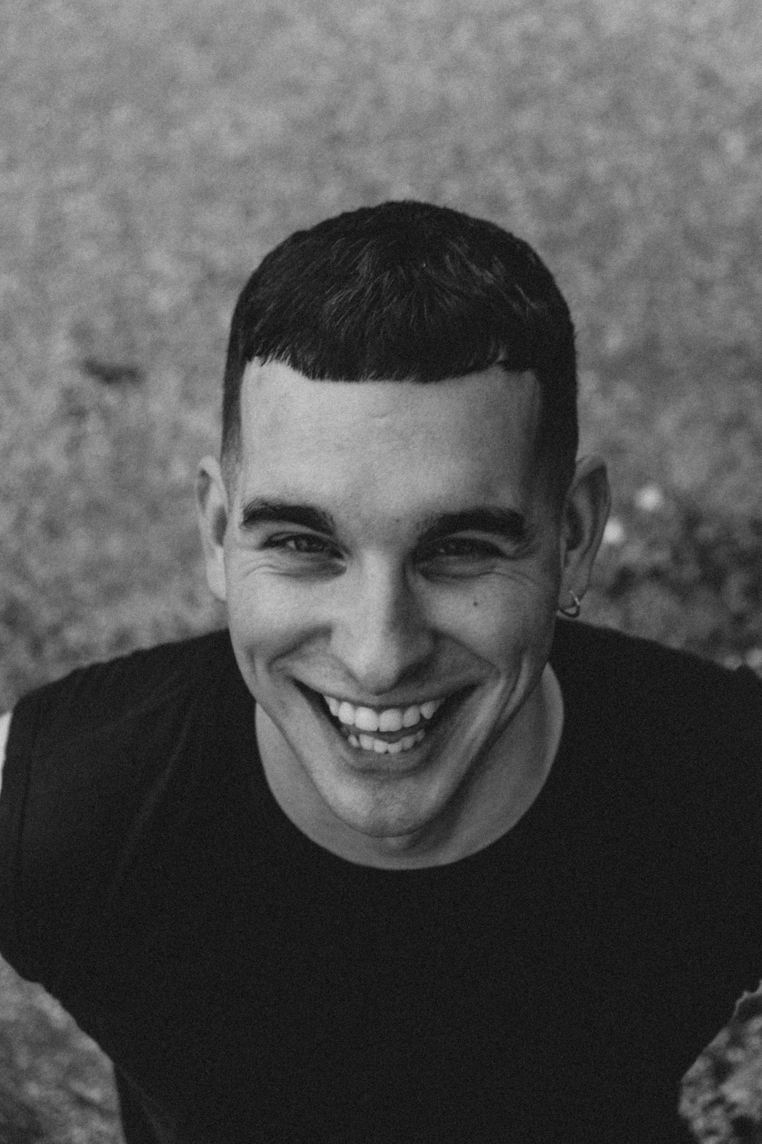 Black and white portrait showing genuine smile and black sleeveless shirt.