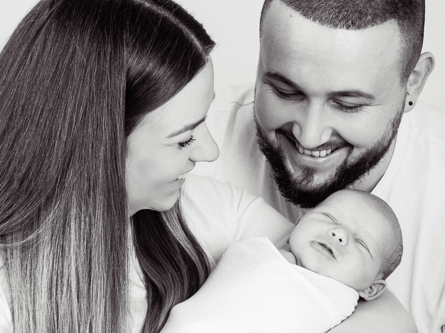 Black and white family portrait series showing tender moments with newborn.