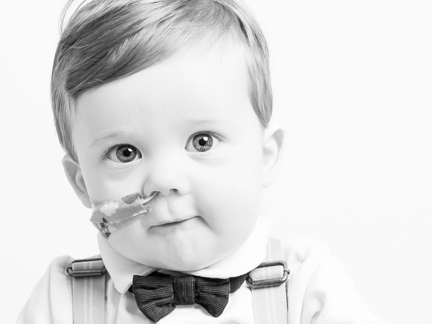 Close-up black and white portraits of baby boy wearing bow tie.