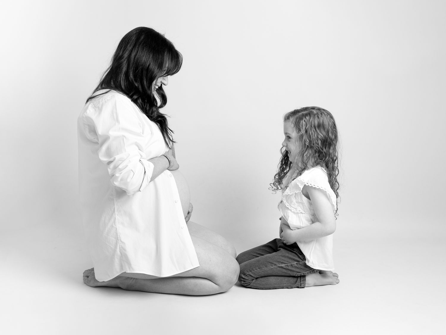 Minimalist lifestyle portraits showing casual family interactions in white studio setting.