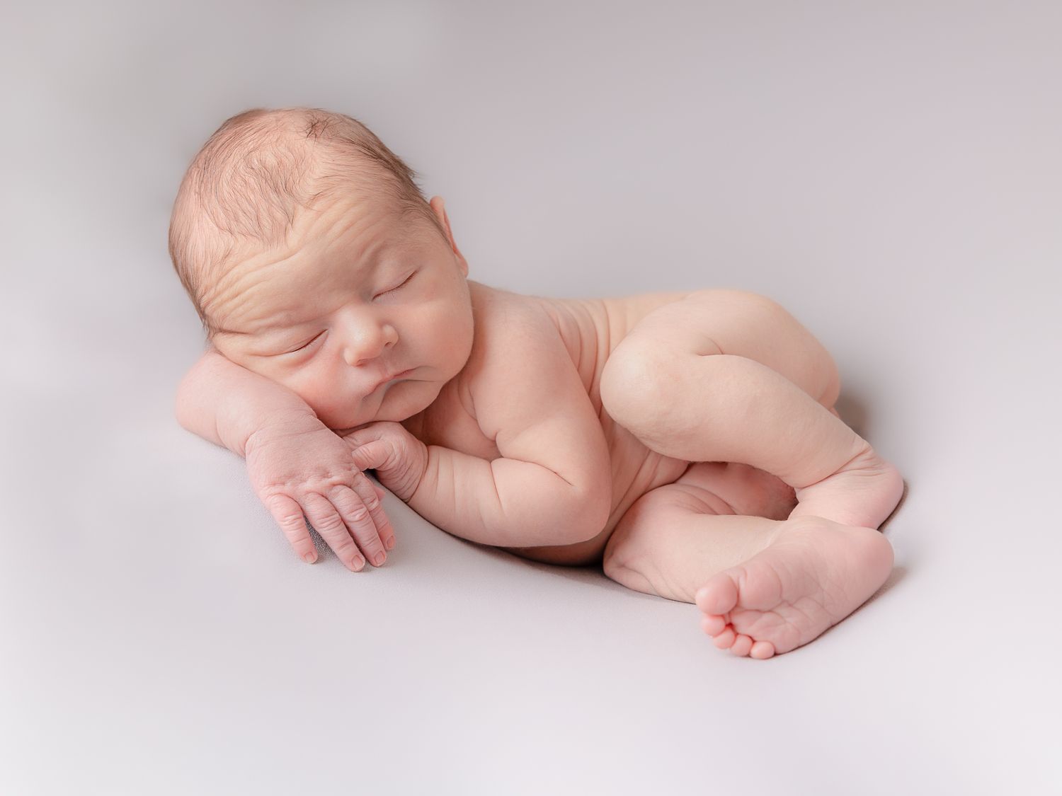 Close-up details of a sleeping newborn baby in soft light and neutral tones.