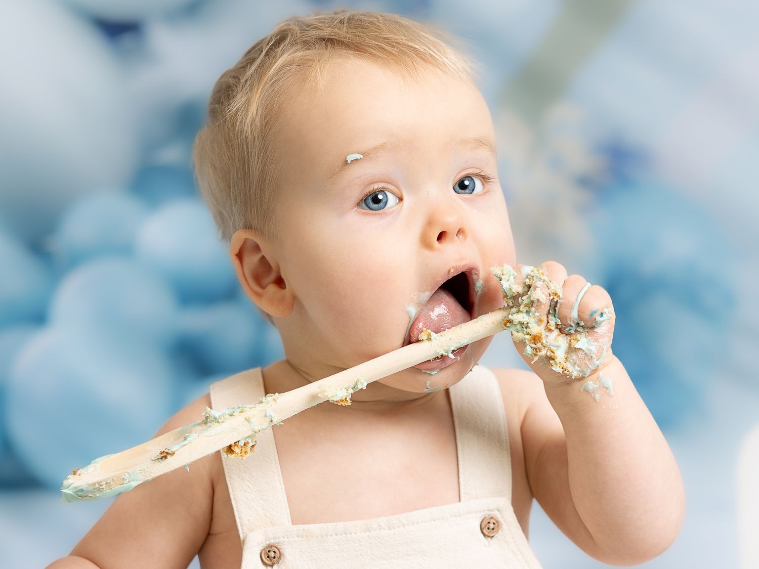Baby eating cake smash photos against blue bokeh background.