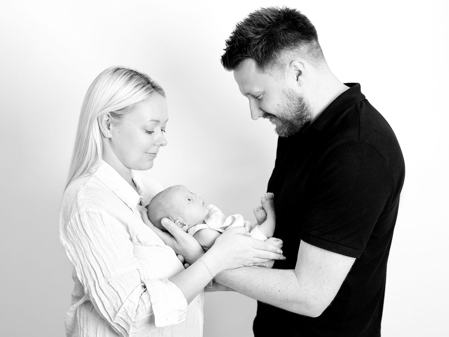 Family bonding moment with newborn baby in black and white.
