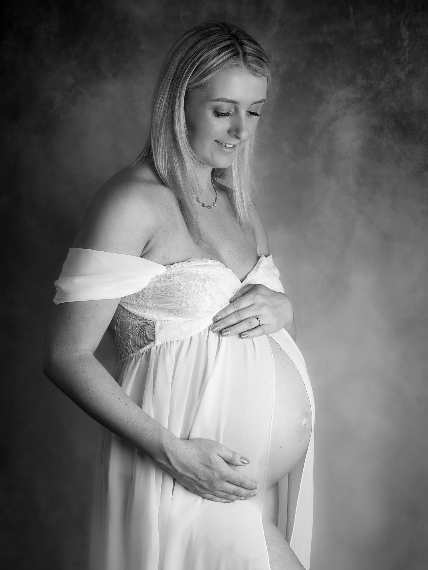 Artistic black and white maternity photos showing expectant mother in flowing white dress.