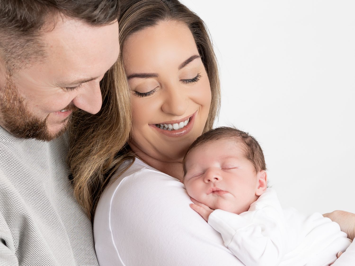 Sweet family moment captured in soft white tones during newborn photo session.