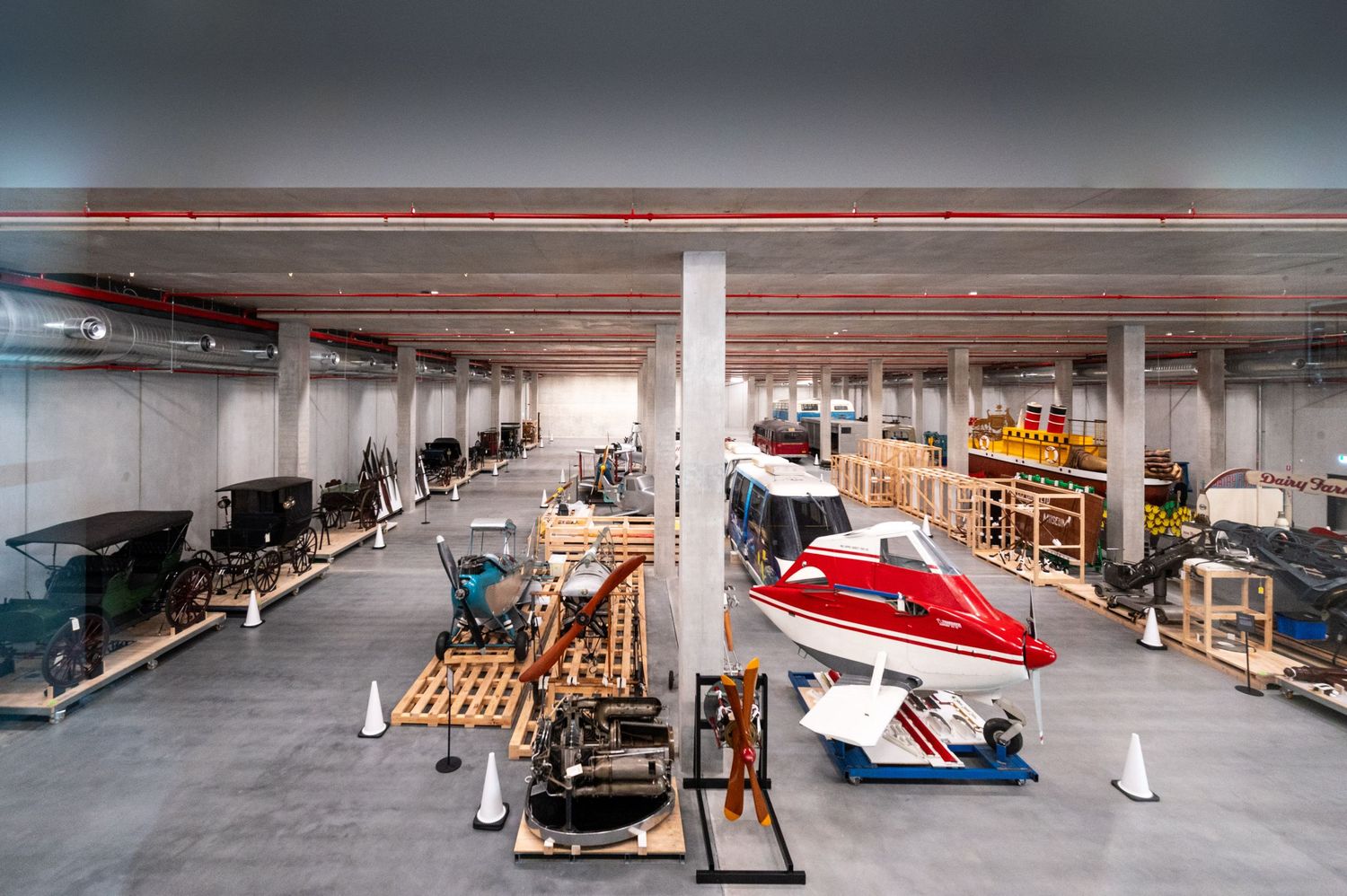 Classic vintage cars on display in a large showroom with white walls and concrete floors.