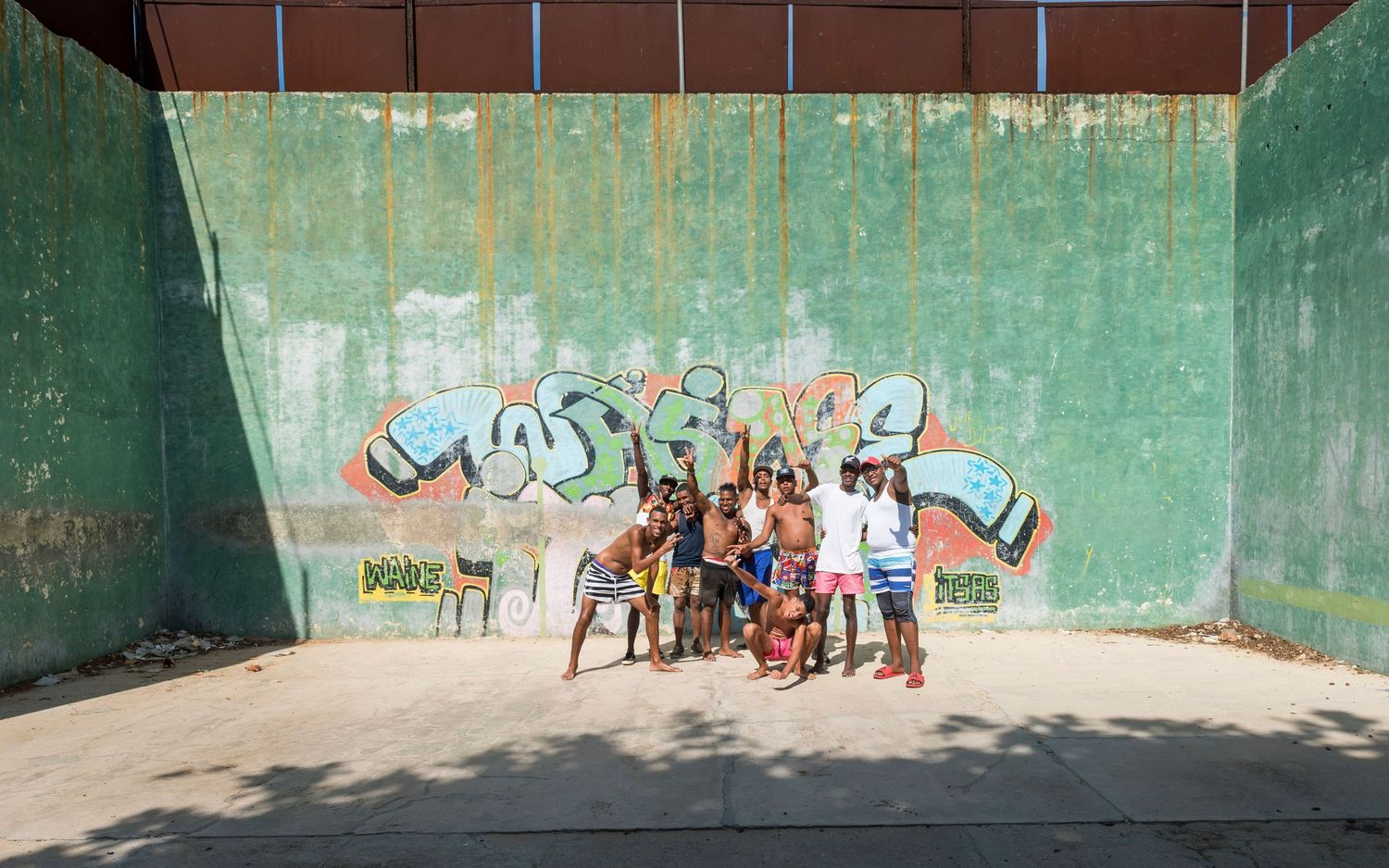 Group gathered in front of graffiti wall in urban setting.