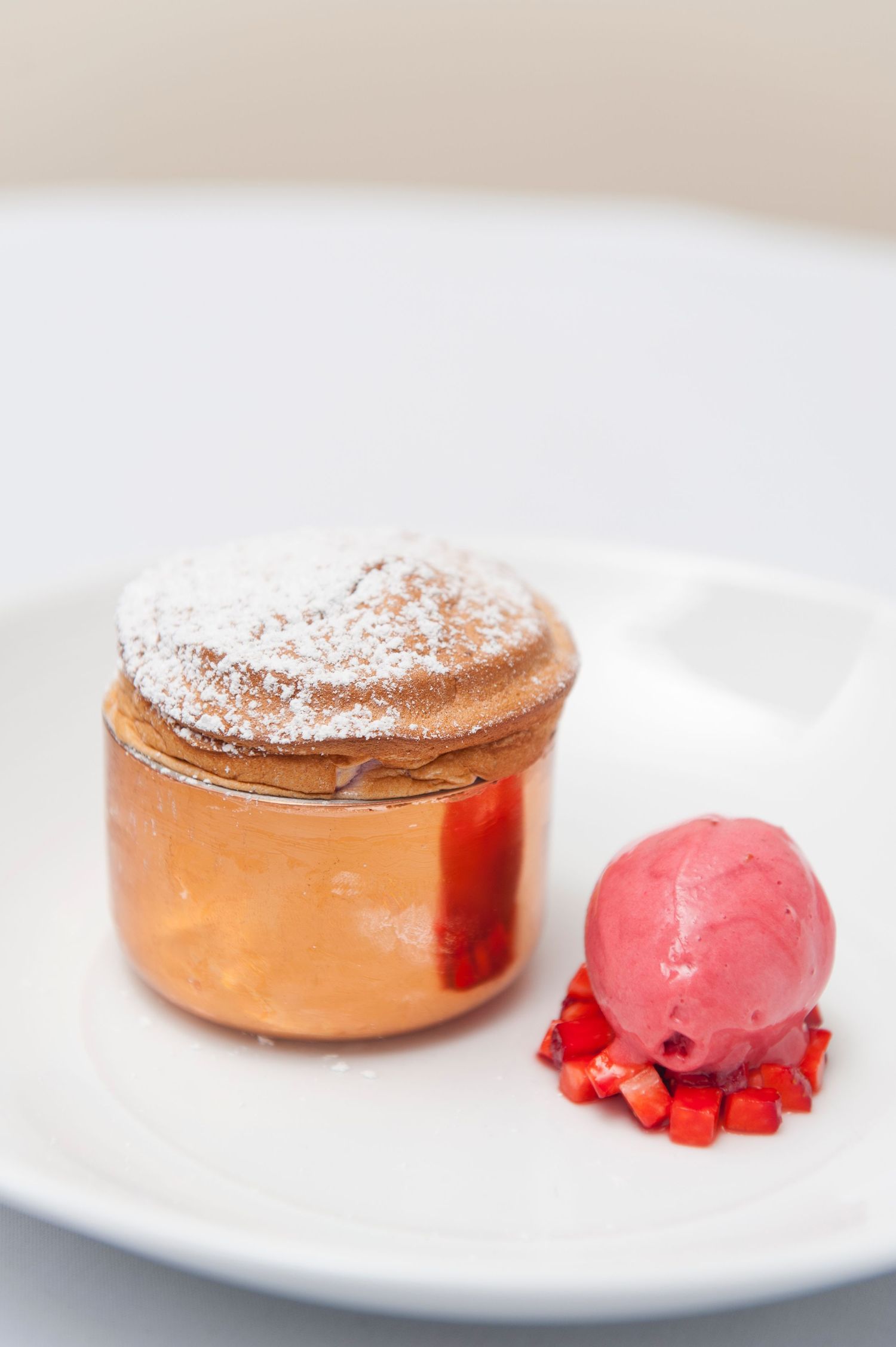 Fine dining dessert plate featuring a dusted pastry and bright pink sorbet garnish.