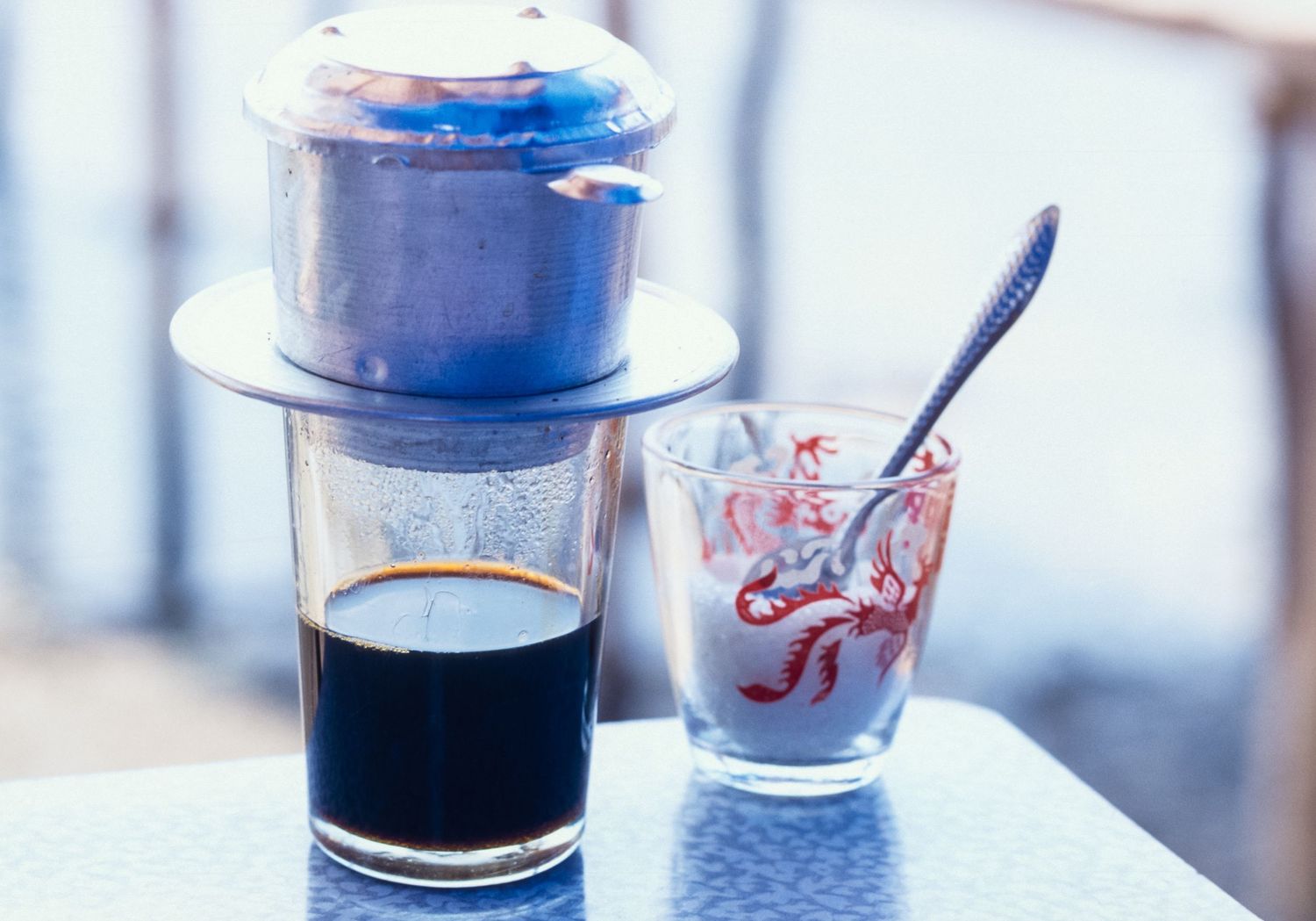 Glass cups with dark liquid and straws on a light colored table.