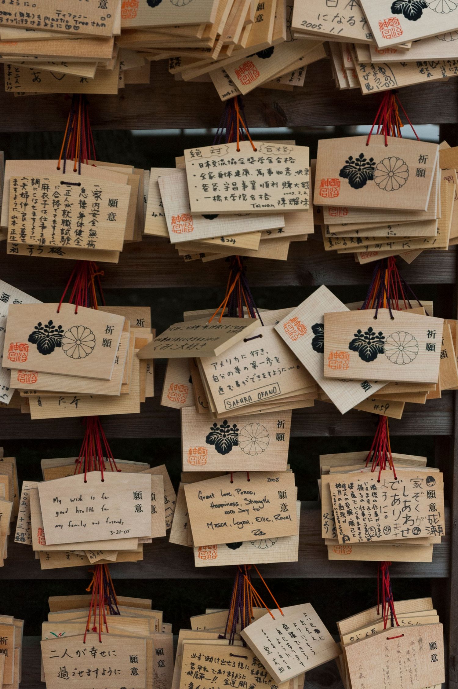 Collection of wooden prayer tablets with Japanese calligraphy hanging at a temple.