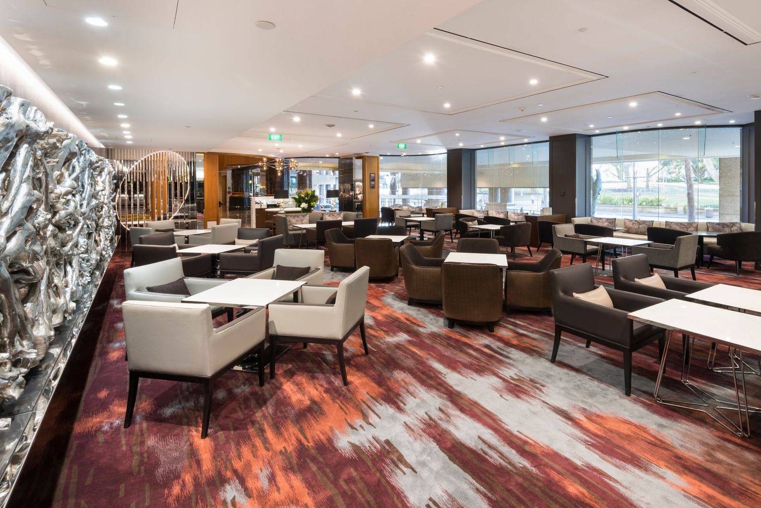 Spacious restaurant seating area with contemporary furniture and striking red patterned carpet.
